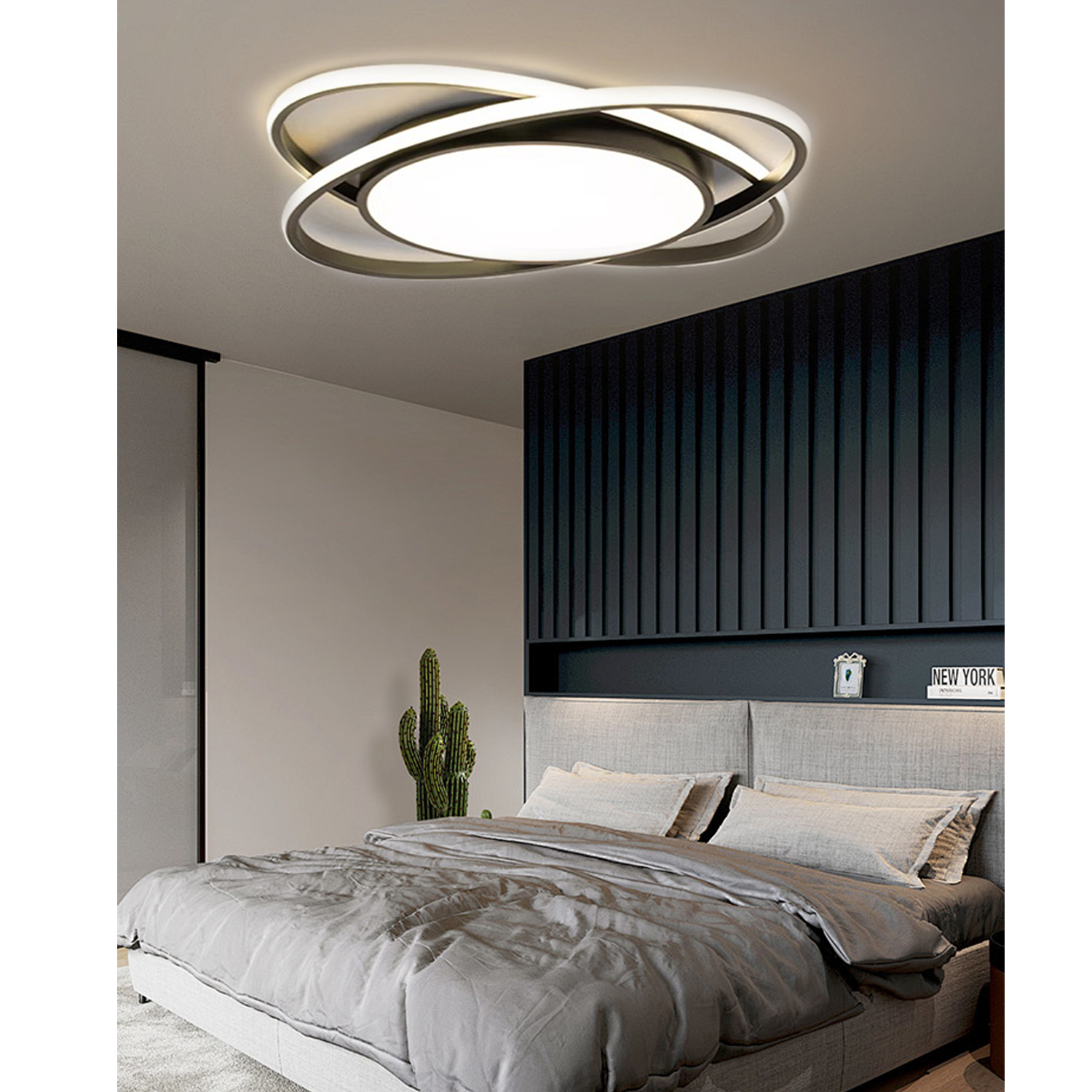 Modernes Schlafzimmer mit Deckenleuchte. Bett mit grauen Laken und Kissen. Kaktus in der Ecke.