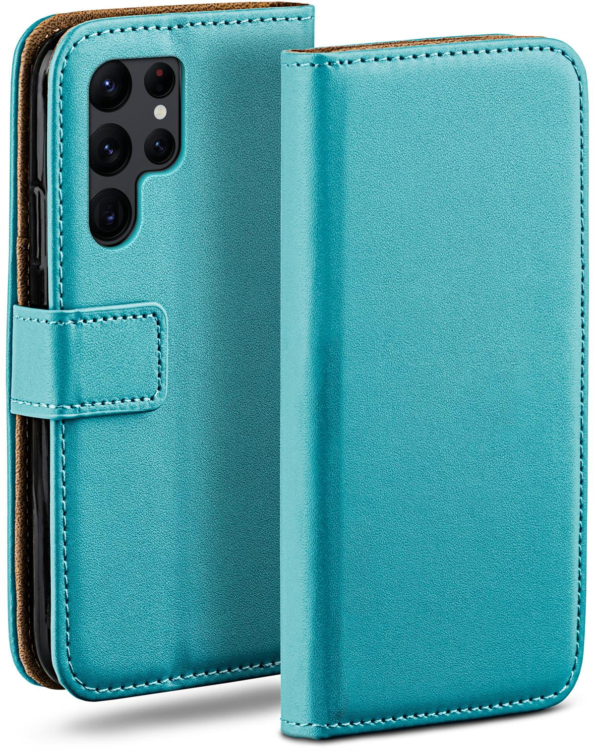 Blaue Leder-Handyhülle, offen. Brauner Innenraum, weiße Nähte. Telefon darin. Verschluss geschlossen.