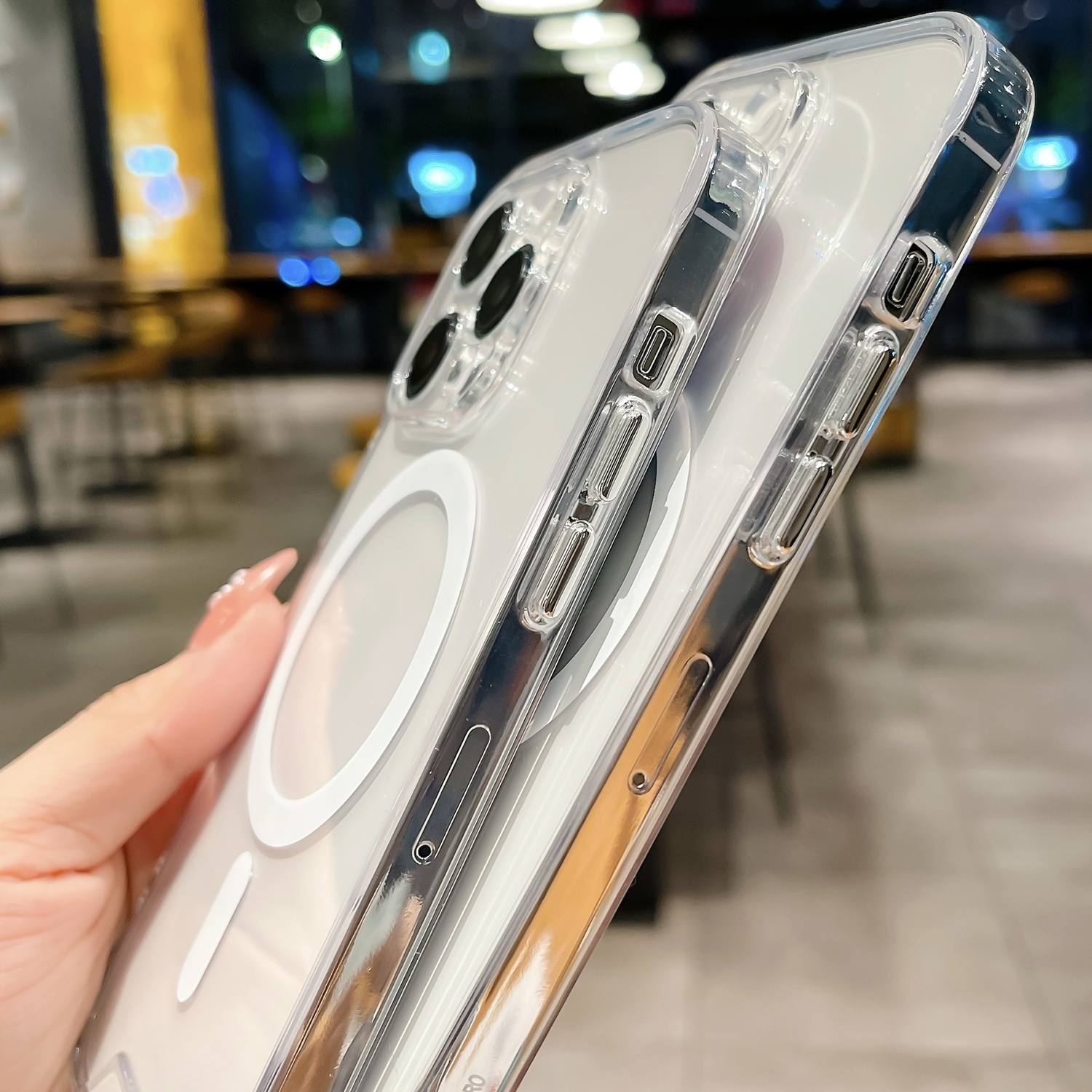 Transparente Handyhülle in der Hand. Die Hülle ist auf einem Telefon. Restaurant im Hintergrund verschwommen.