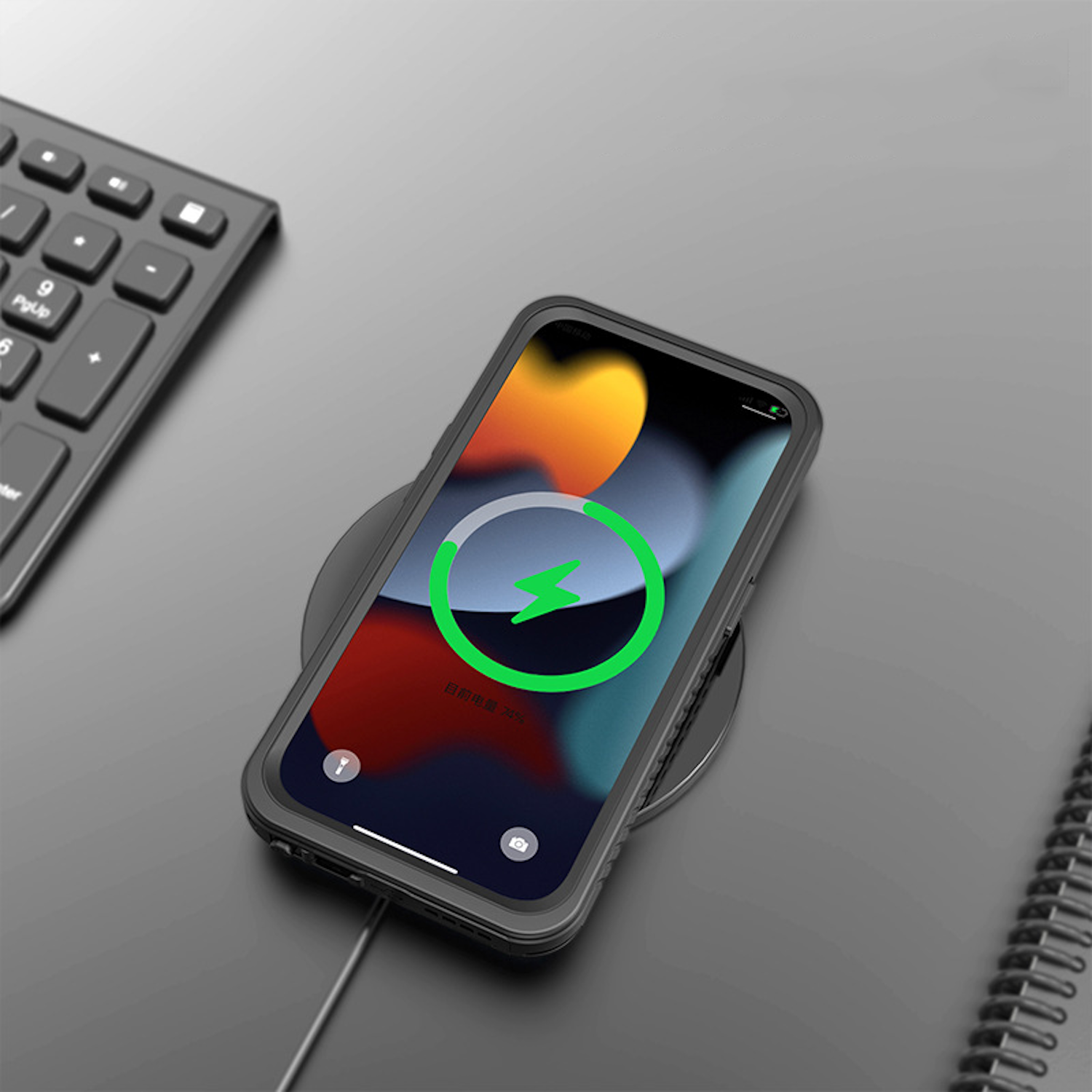 Telefon auf kabellosem Ladegerät, lädt, mit Tastatur und Notizbuch im Hintergrund.