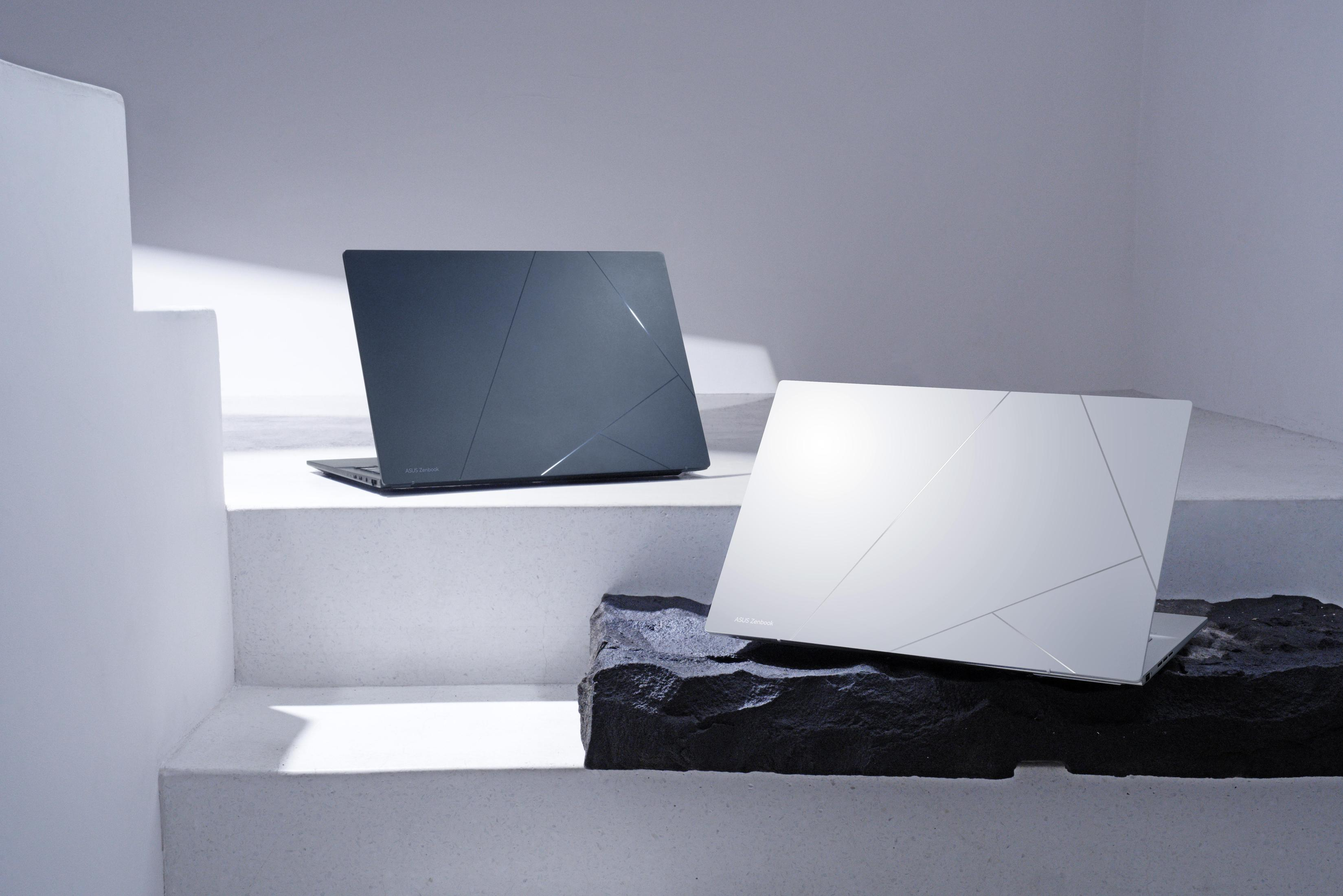 Due laptop con lo stesso design. Uno bianco, l'altro grigio. Su scale bianche e una pietra.