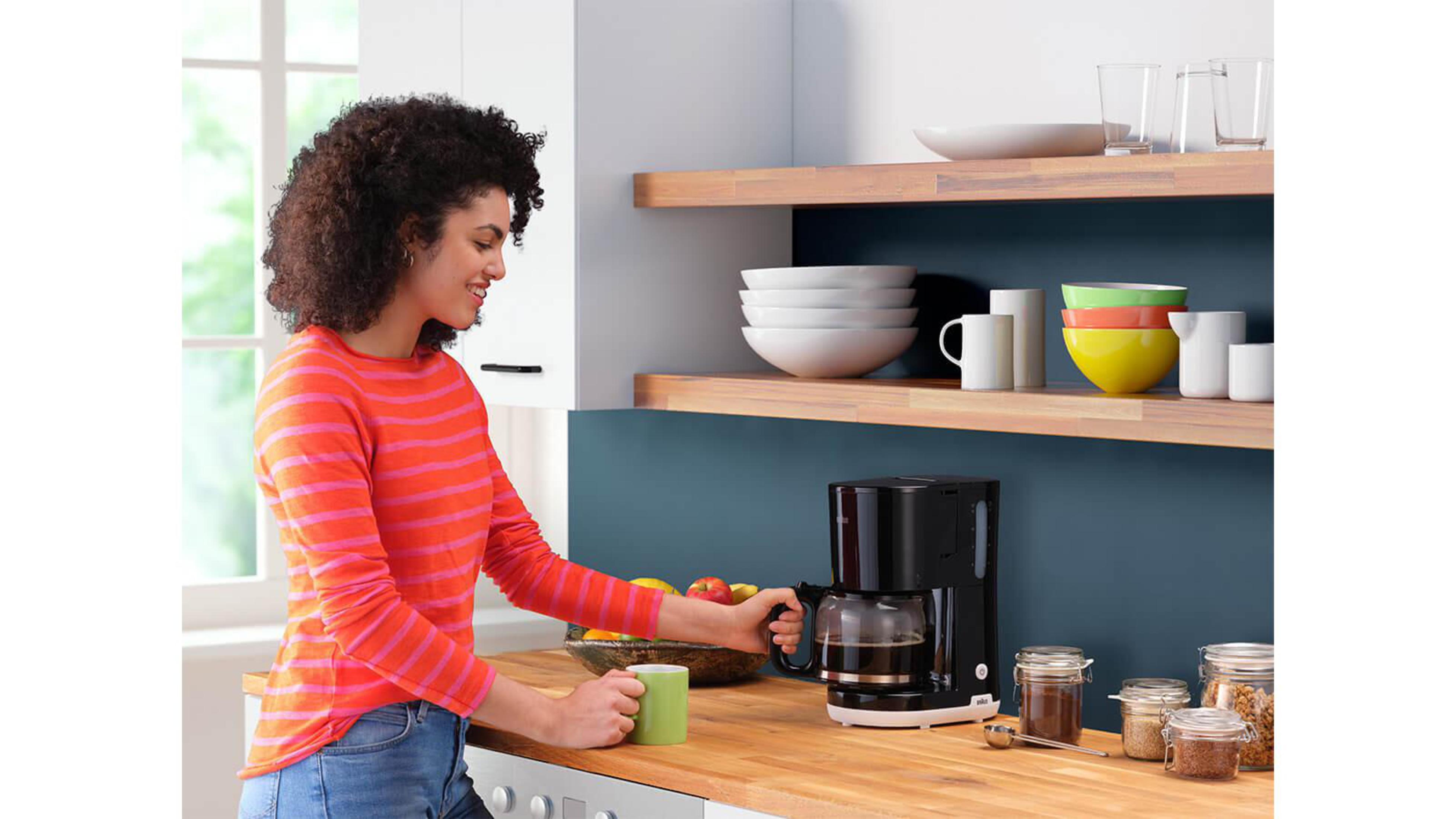 Kobieta w kuchni robiąca kawę, z ekspresem do kawy i innymi przedmiotami.