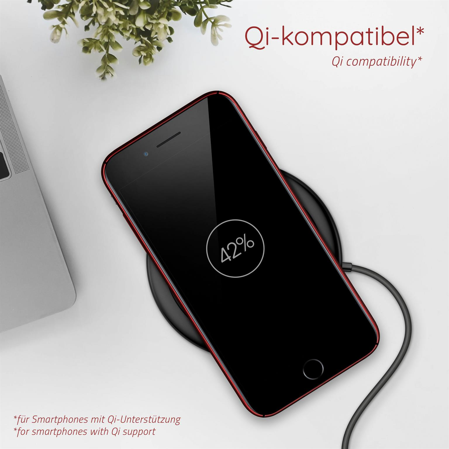 Telefon auf kabellosem Ladegerät. Bildschirm zeigt 42%. Hülle ist rot. Pflanze und Laptop sichtbar.