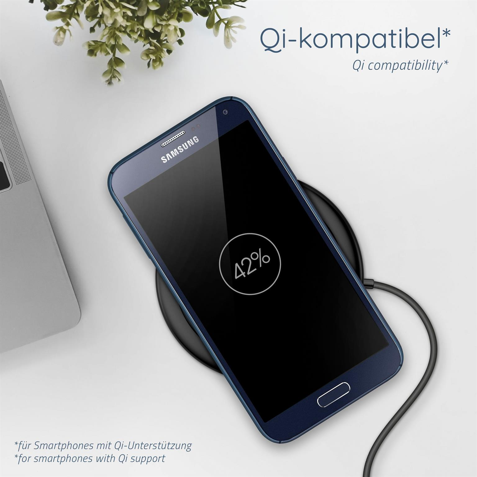 Telefon lädt kabellos, zeigt 42% Akku. Ladepad und Laptop im Hintergrund.
