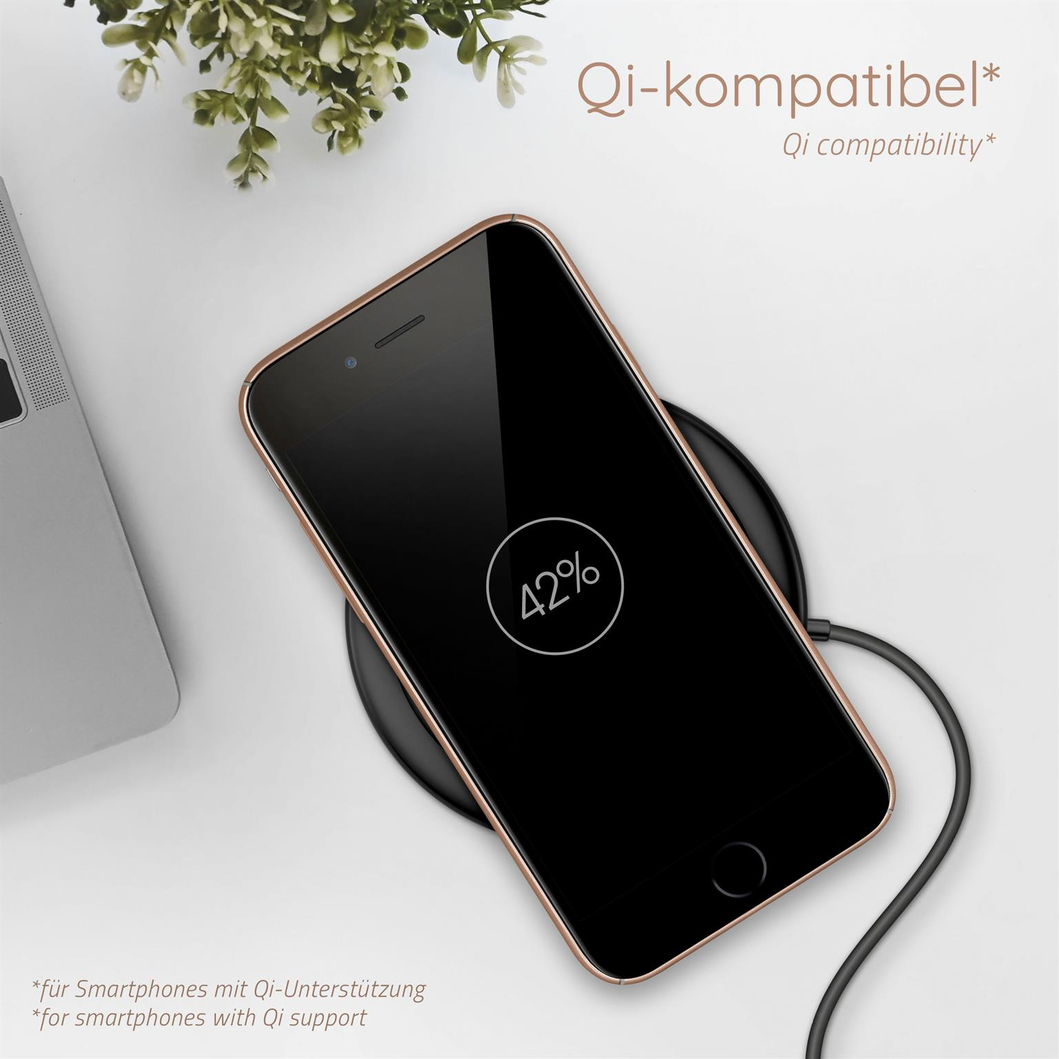 Telefon lädt auf kabellosem Pad. Telefon zeigt 42%. Hintergrund zeigt Blumen und einen Laptop.