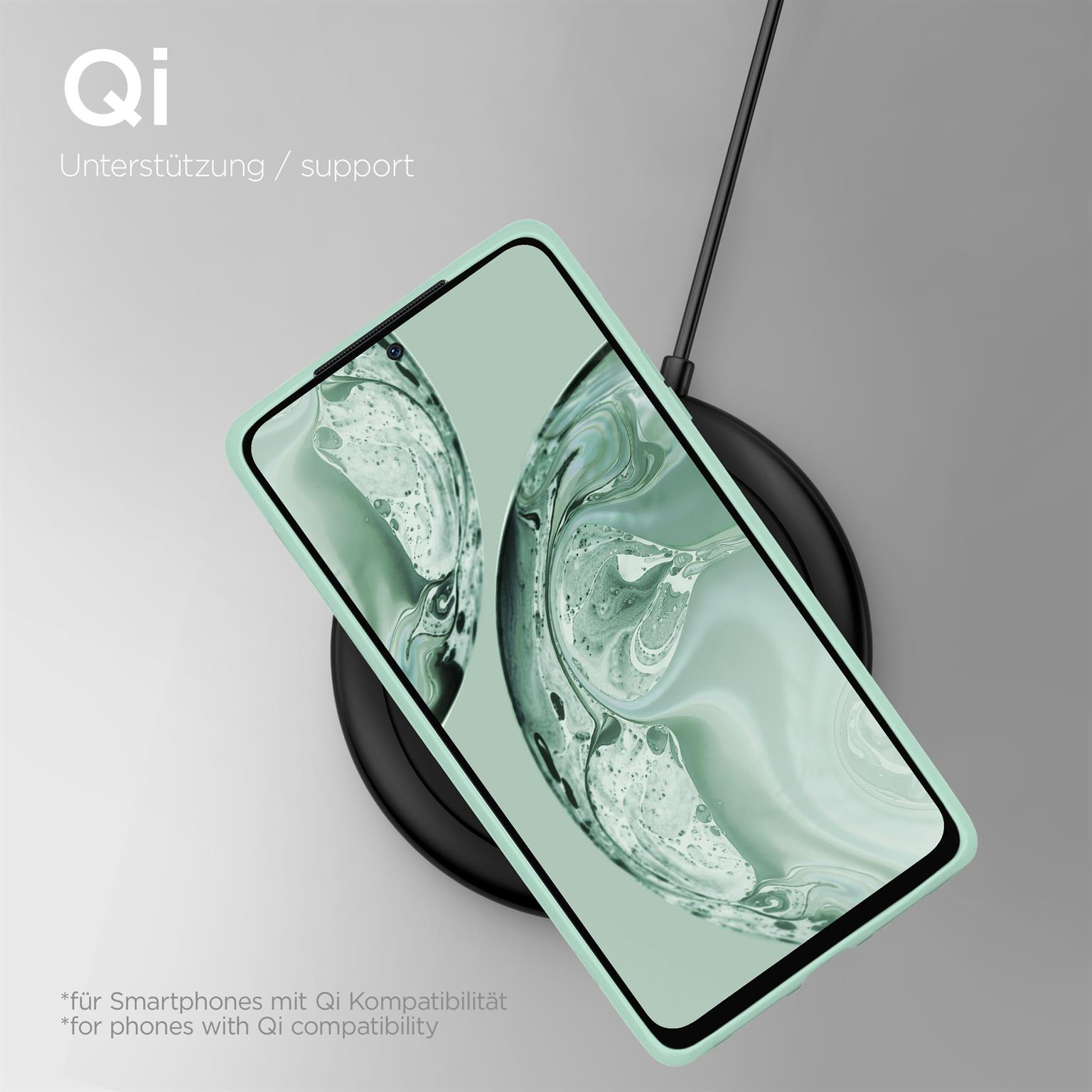Telefon in grüner Hülle auf kabellosem Ladegerät. Schwarzes Pad, weißer Hintergrund.