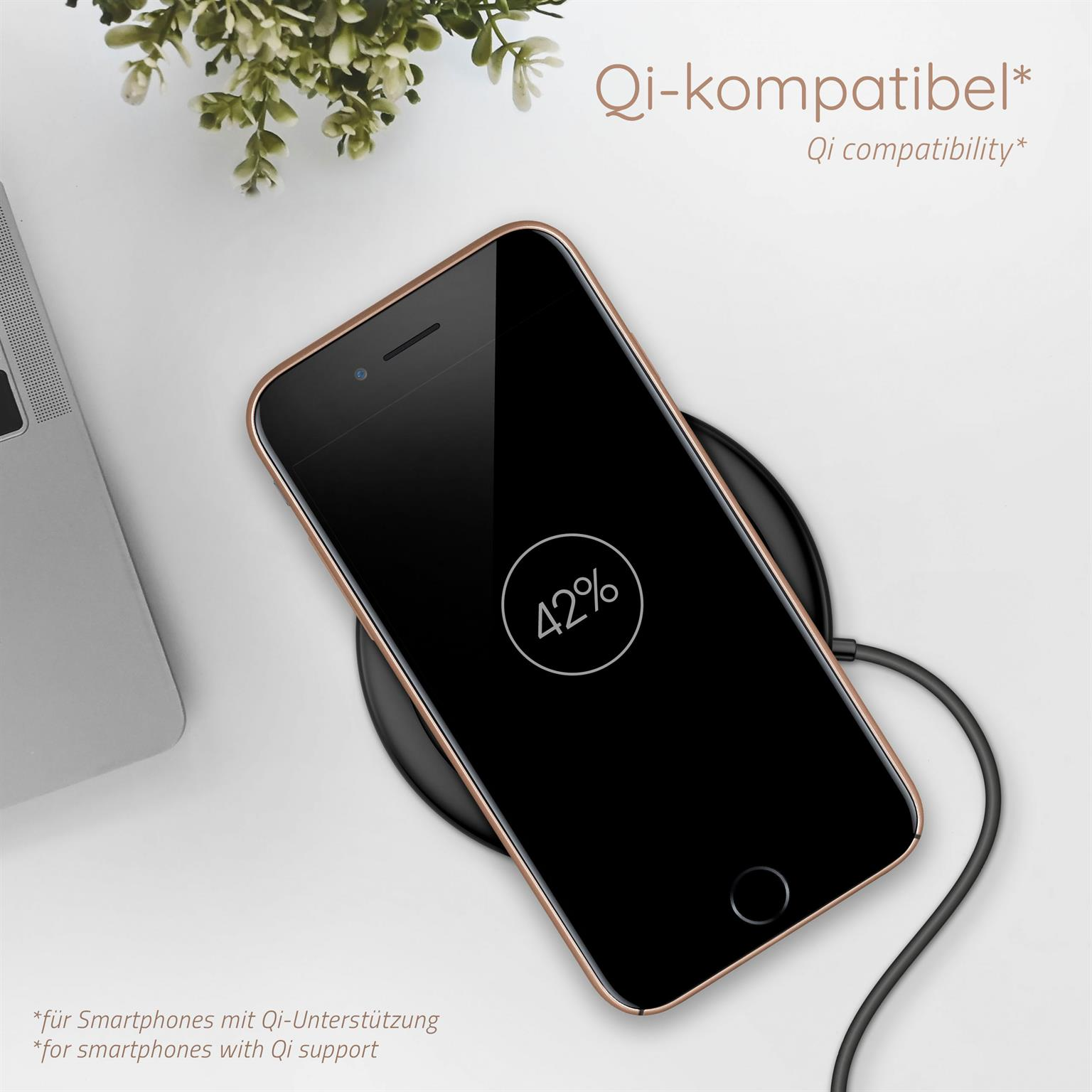 Telefon lädt kabellos, zeigt 42% Akku. Ladepad und Laptop im Hintergrund.