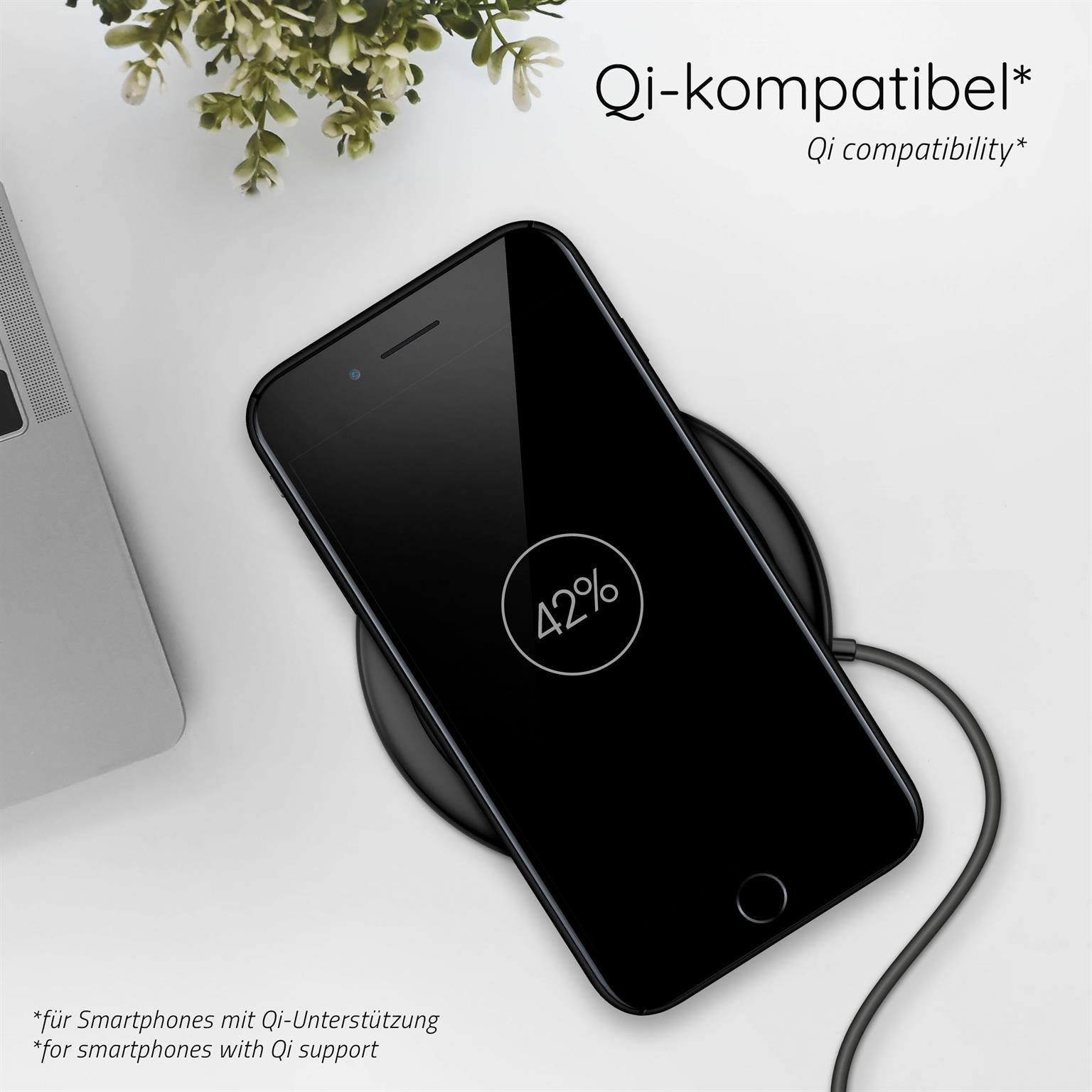 Schwarzes Telefon auf kabellosem Ladegerät, zeigt 42% Akku. Weißer Hintergrund, mit Pflanze und Laptop.