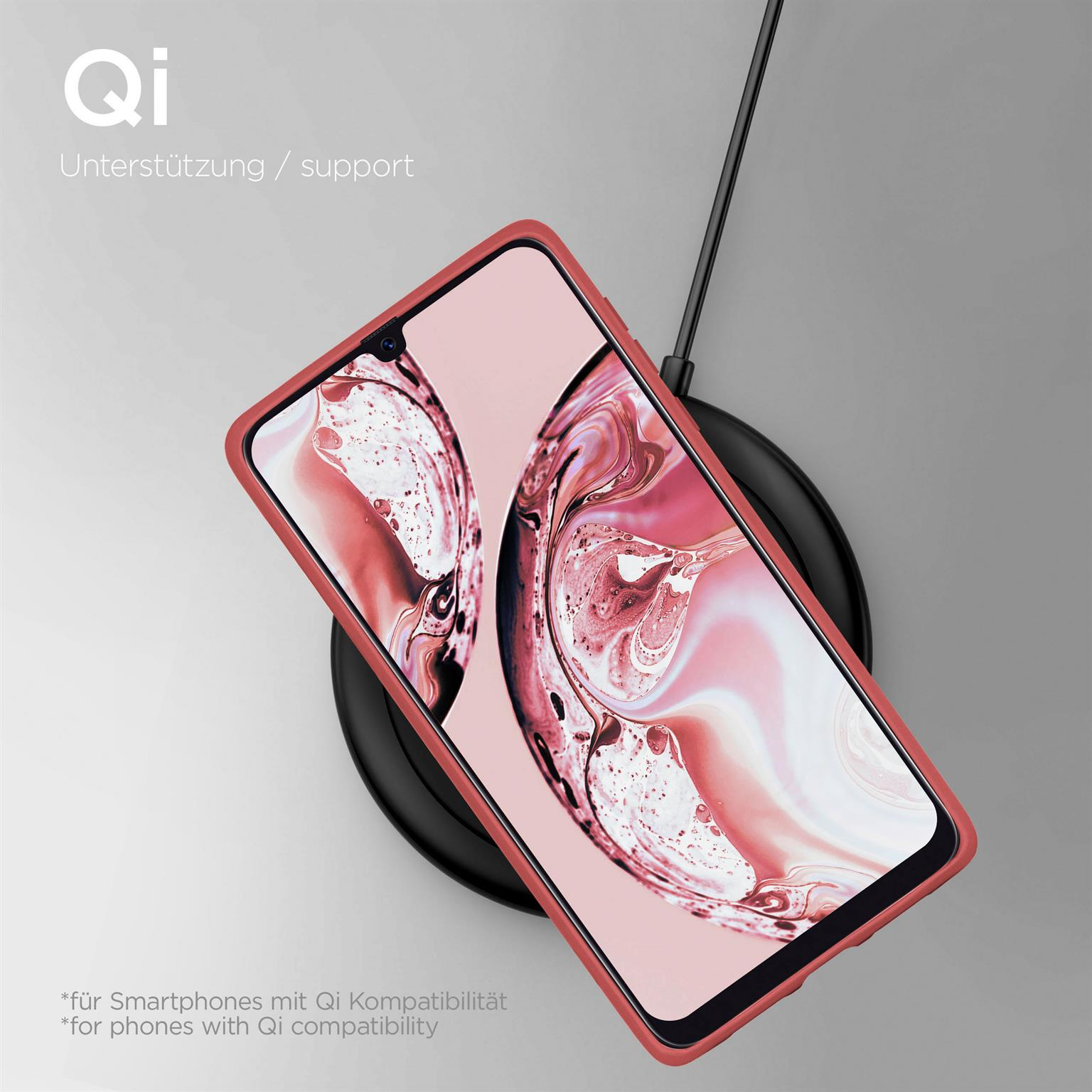 Ein Telefon in roter Hülle, das auf einem kabellosen Ladegerät geladen wird, mit Text zur Qi-Kompatibilität.