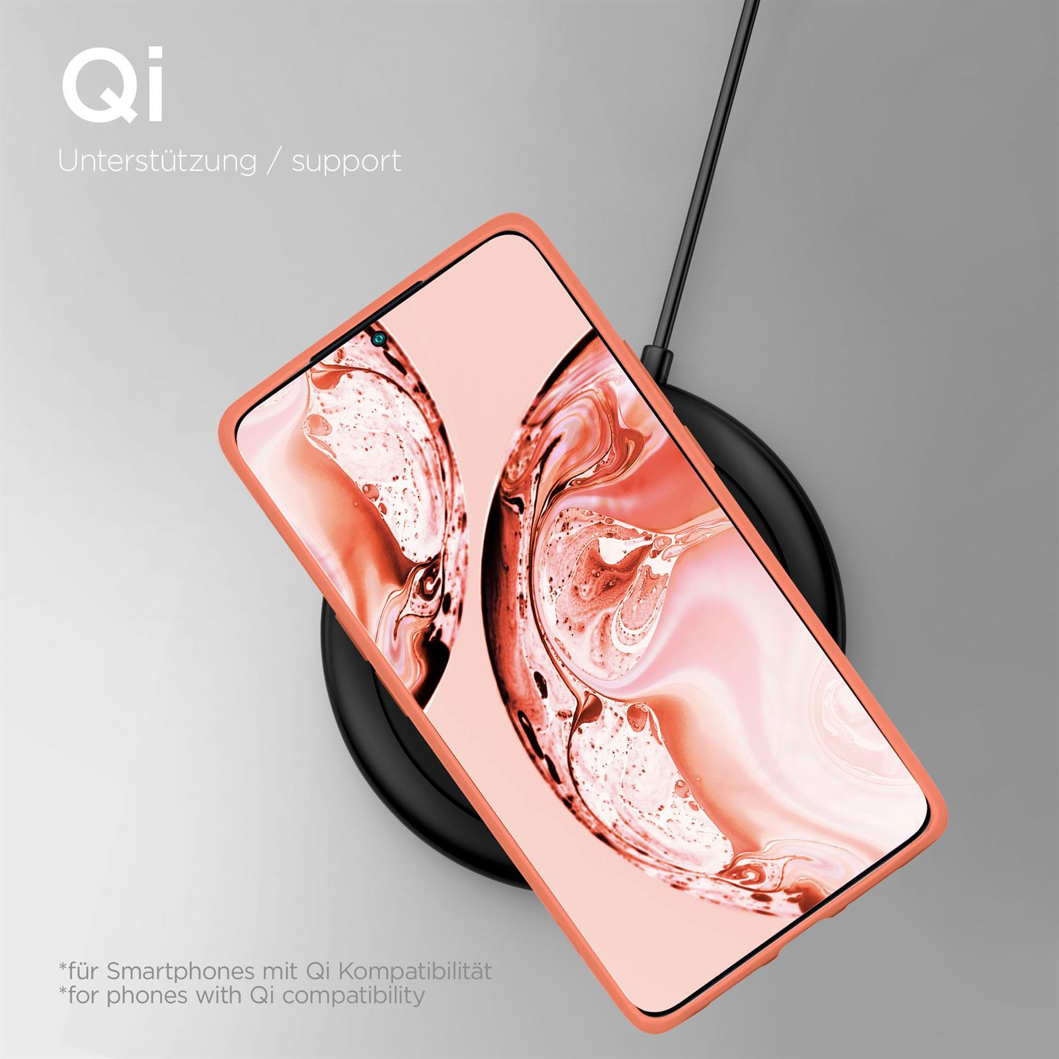 Ein pfirsichfarbenes Telefon in einer Hülle liegt auf einem kabellosen Ladegerät. Telefon ist abgewinkelt, Hintergrund unscharf.