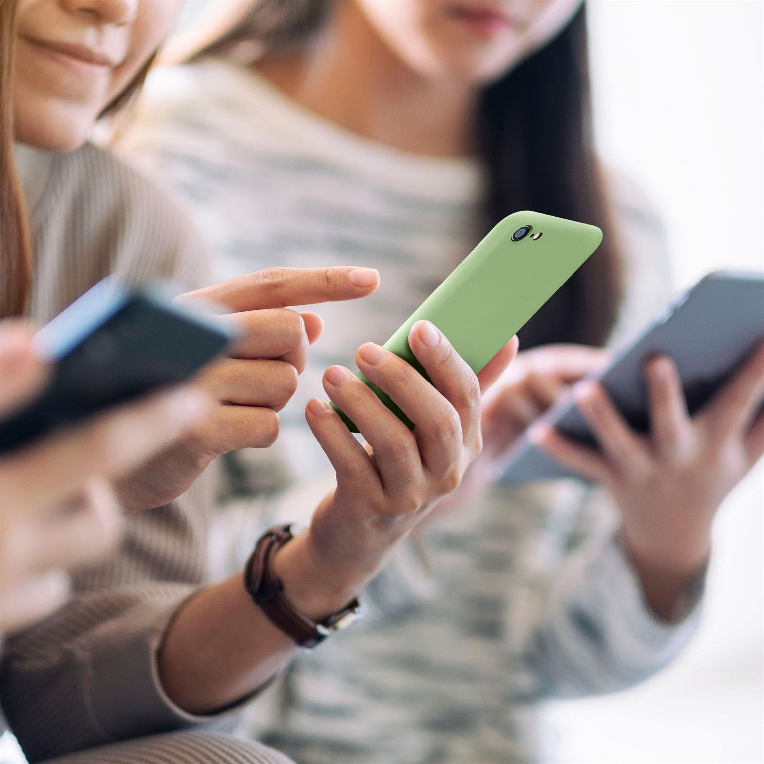 Drei Personen halten Telefone. Eine Person hält ein grünes, andere dunkle Telefone.