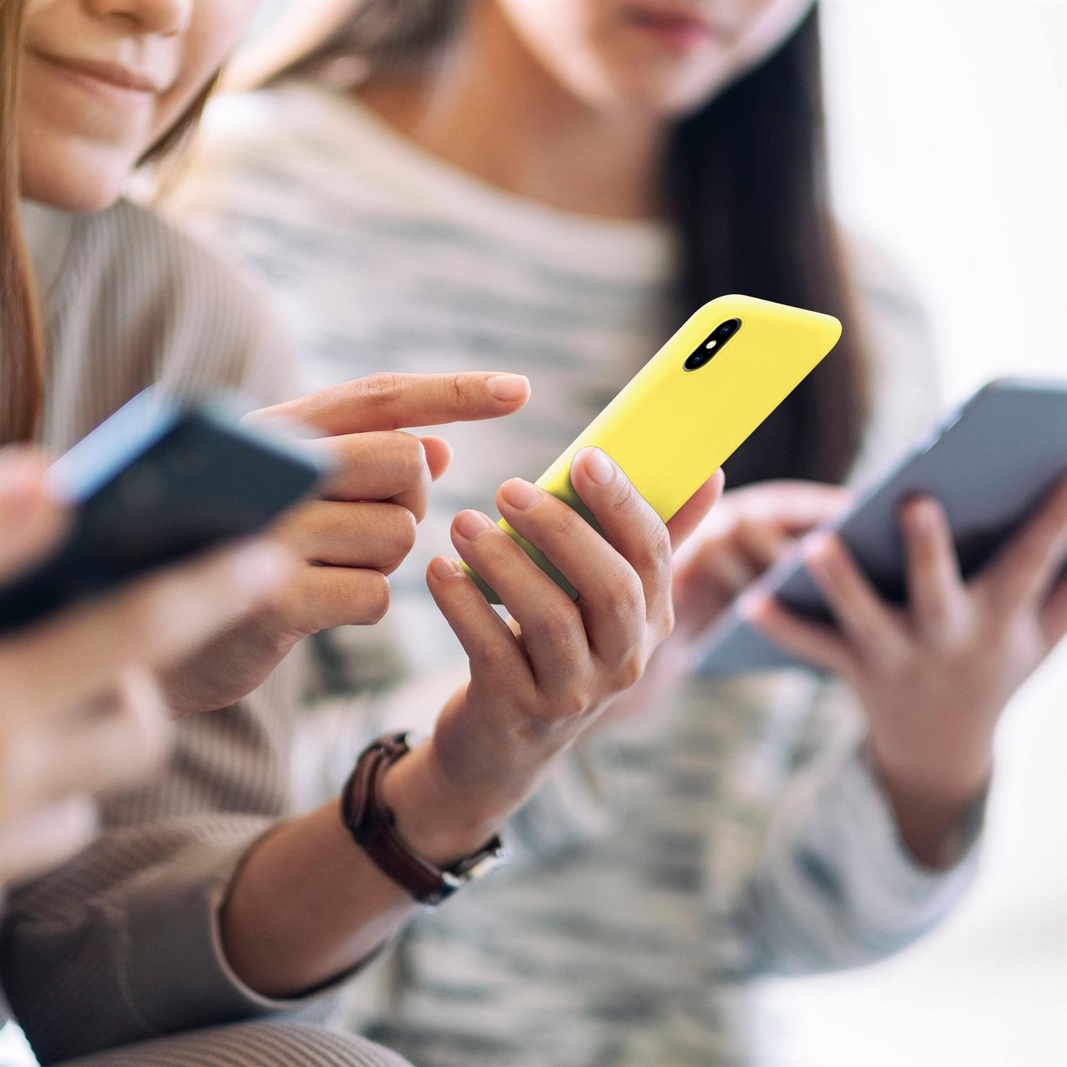 Drei Personen mit Telefonen. Einer hält ein gelbes Telefon, andere halten schwarze und graue Telefone.
