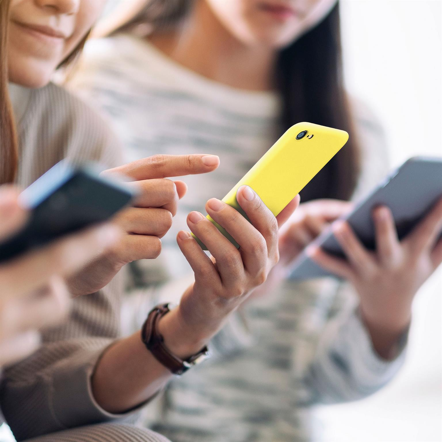 Zwei Frauen halten Telefone. Die erste hält ein gelbes Telefon und die zweite hält ein Telefon in der Hand.