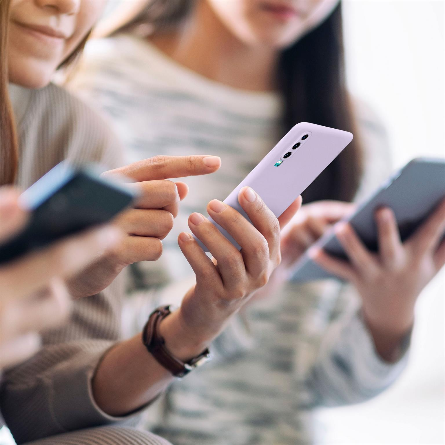 Zwei Frauen halten Telefone. Eine hält eine lila Handyhülle, die andere eine dunkelgraue.