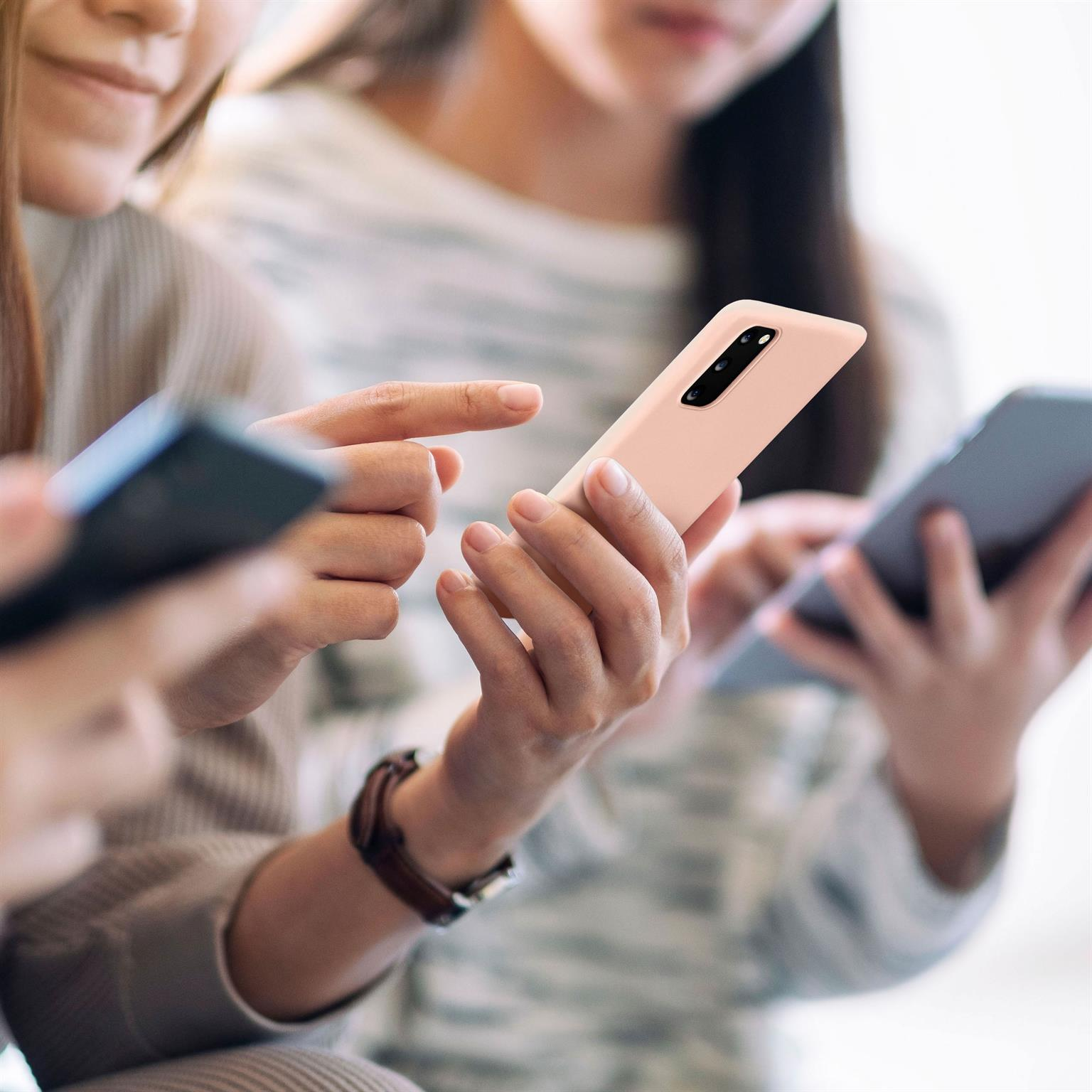 Drei Personen mit Smartphones, eine mit rosa Handyhülle. Selektiver Fokus.