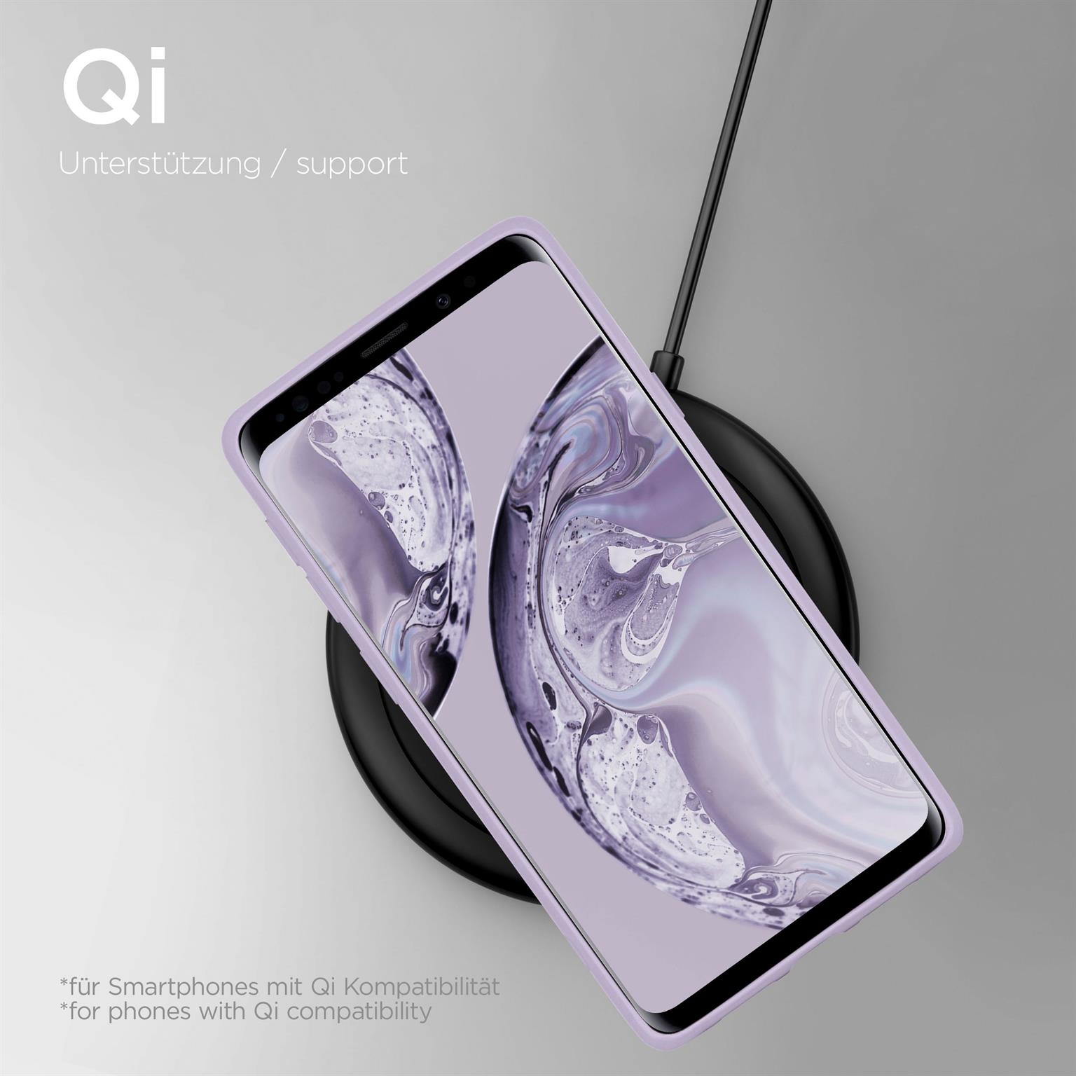 Ein Telefon in einem lila Gehäuse auf einem schwarzen kabellosen Ladegerät. Text oben und unten im Bild.