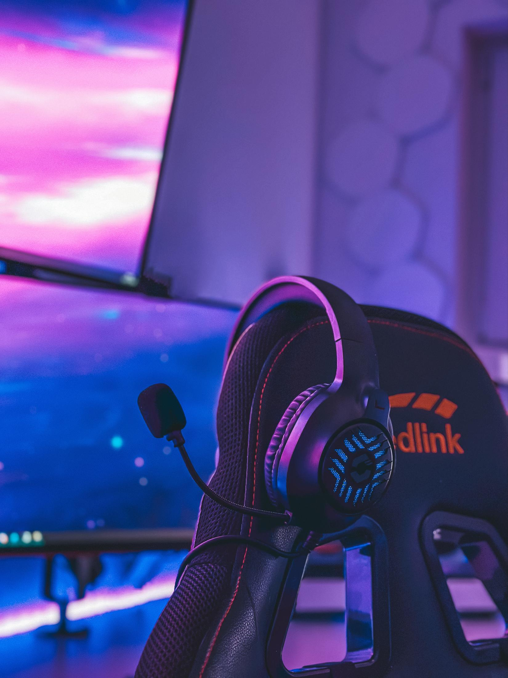 Gaming headset with microphone on black chair. Purple and blue lighting.