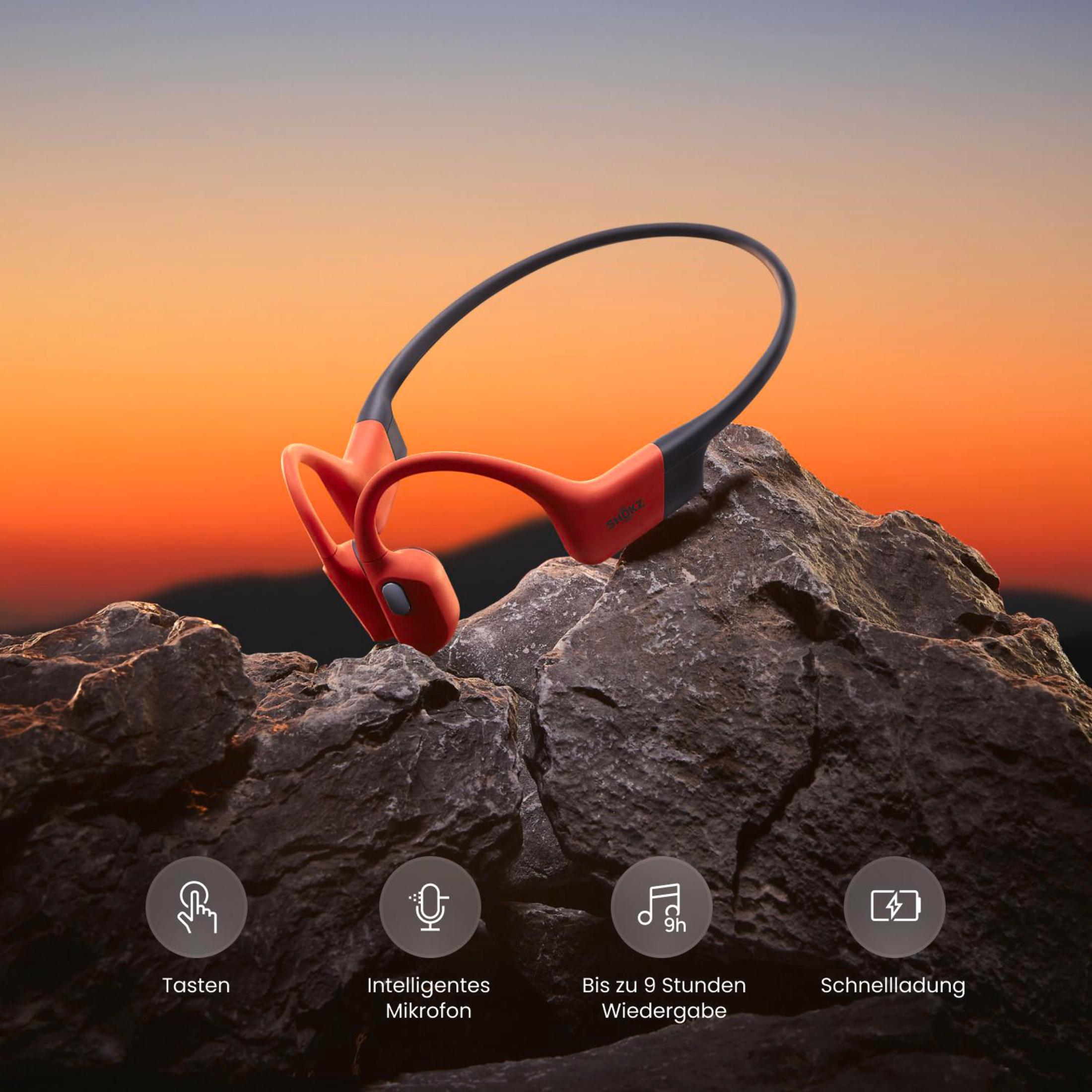 Czerwono-czarne słuchawki sportowe na skalistym krajobrazie.