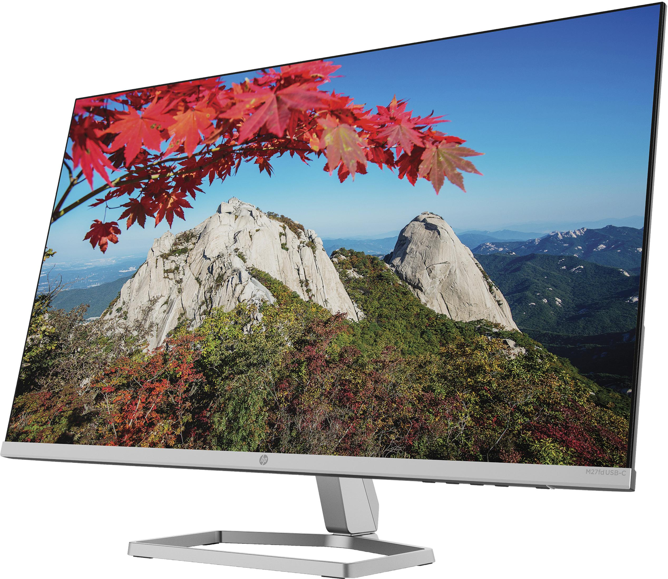 Un monitor di computer con un'immagine panoramica. L'immagine è di montagne e foglie rosse.
