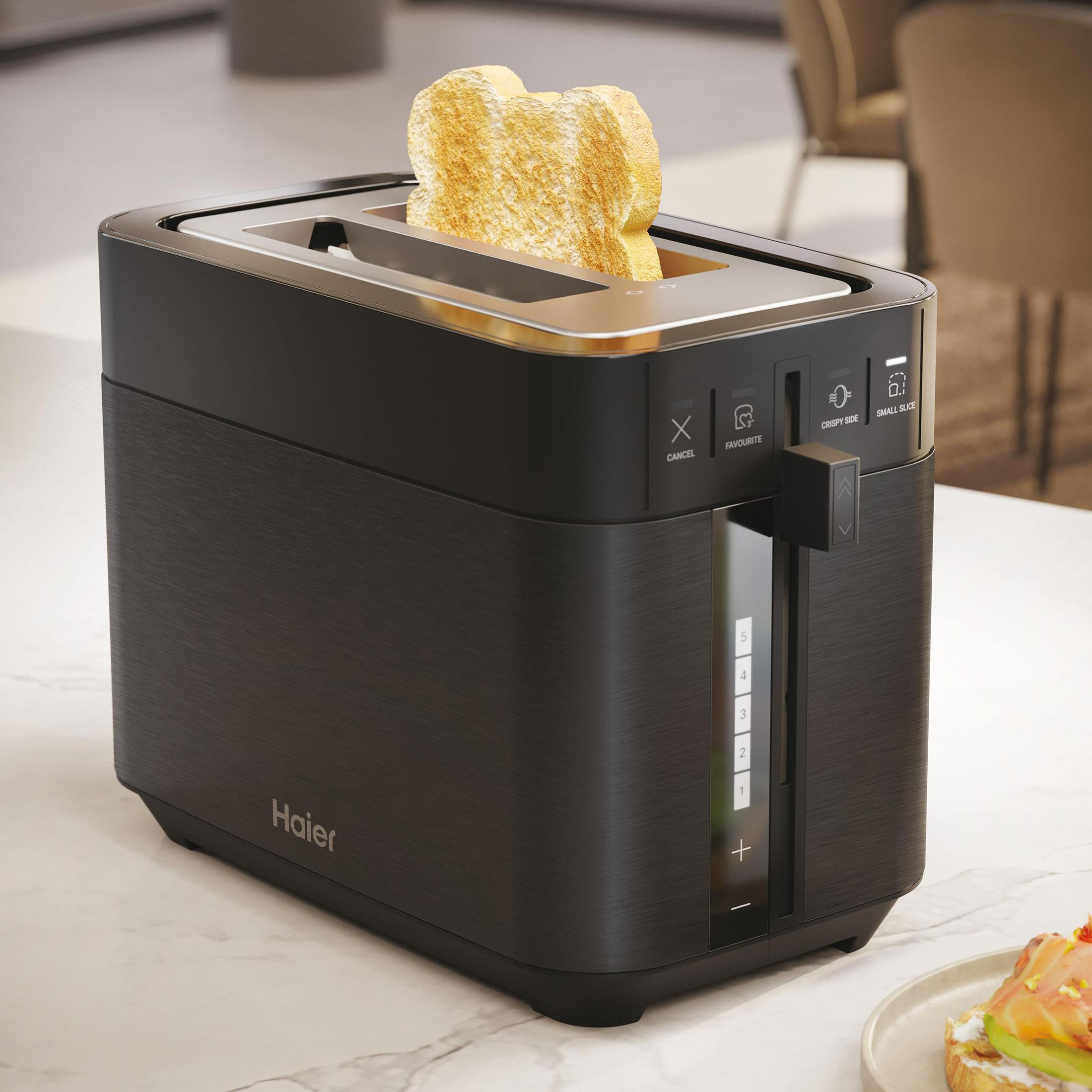 Czarny toster z kromką tostowanego chleba. Toster stoi na białej powierzchni.