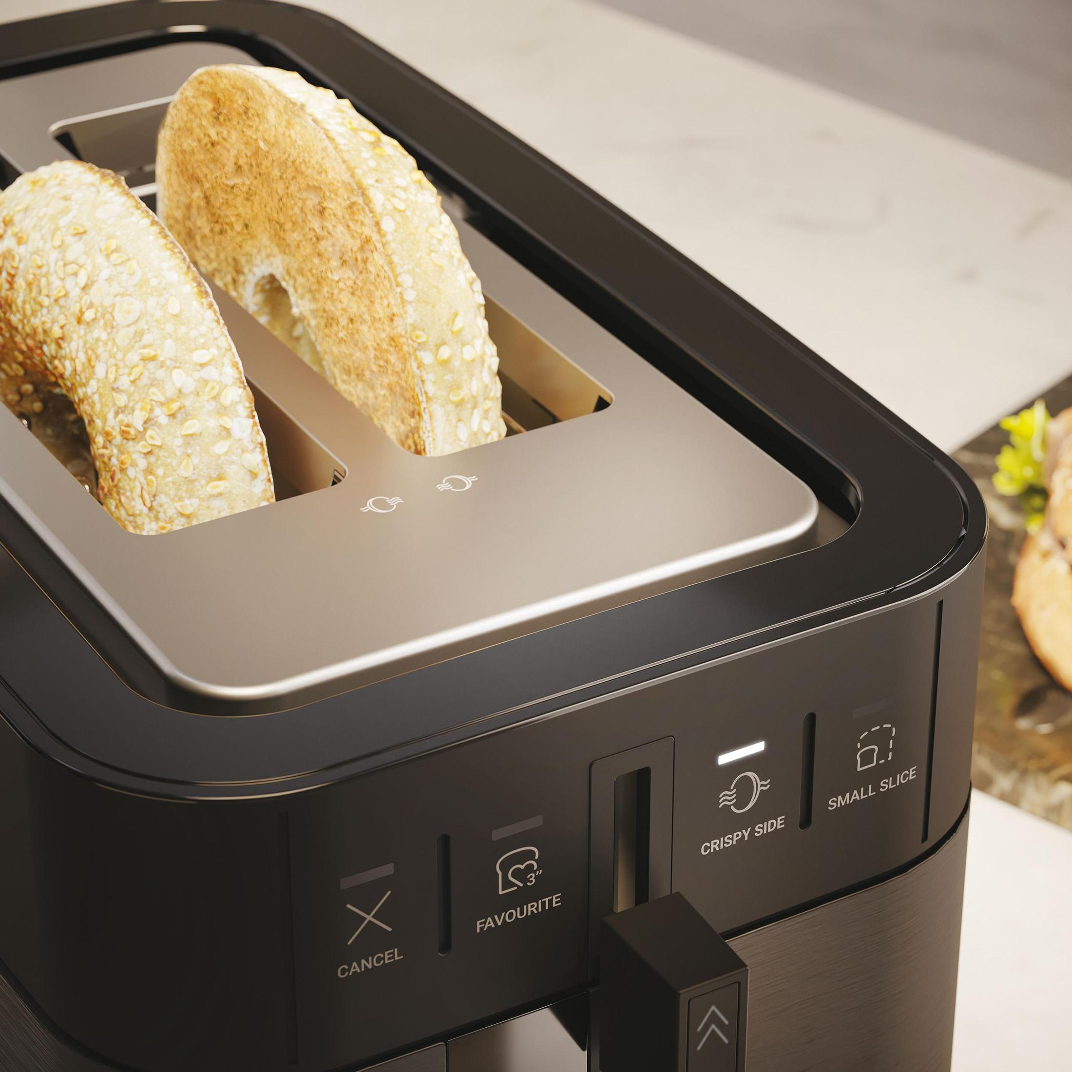 Czarny toster z dwoma bajglami w środku, widoczne elementy sterujące.