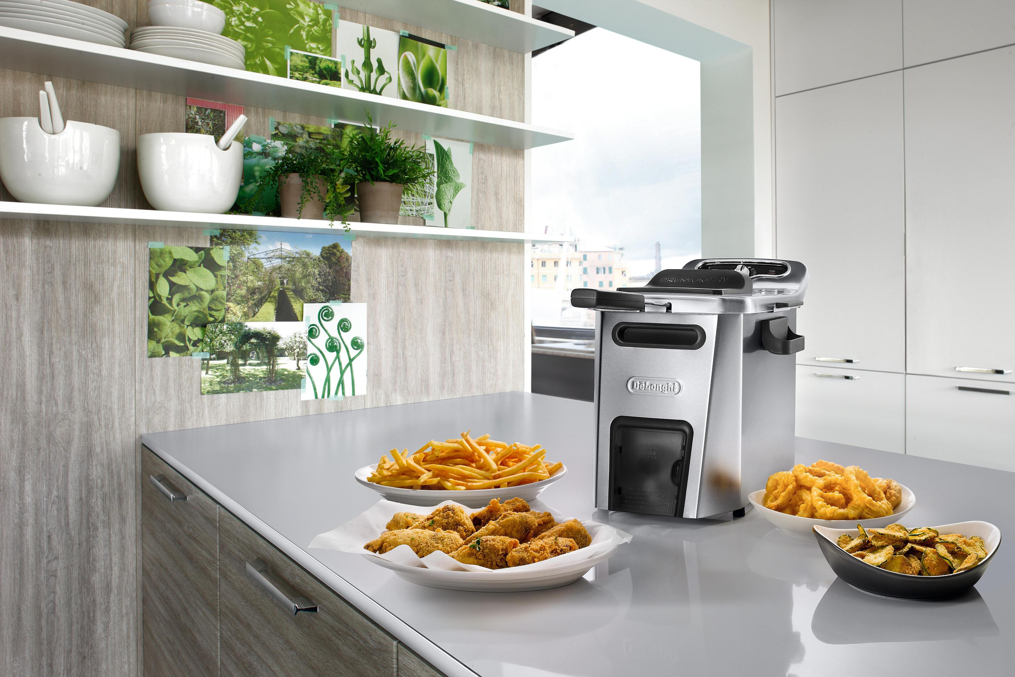 Una escena de cocina con comida frita en platos y una freidora.