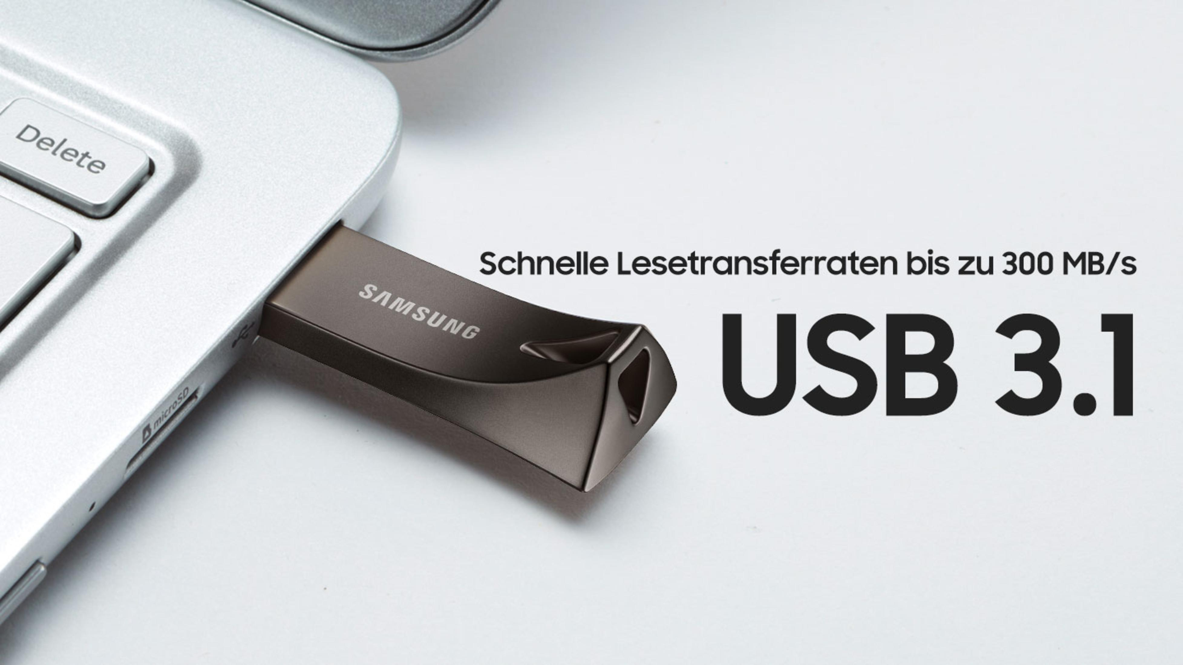 Una unidad flash USB 3.1 plateada con texto. La imagen está sobre un fondo blanco.