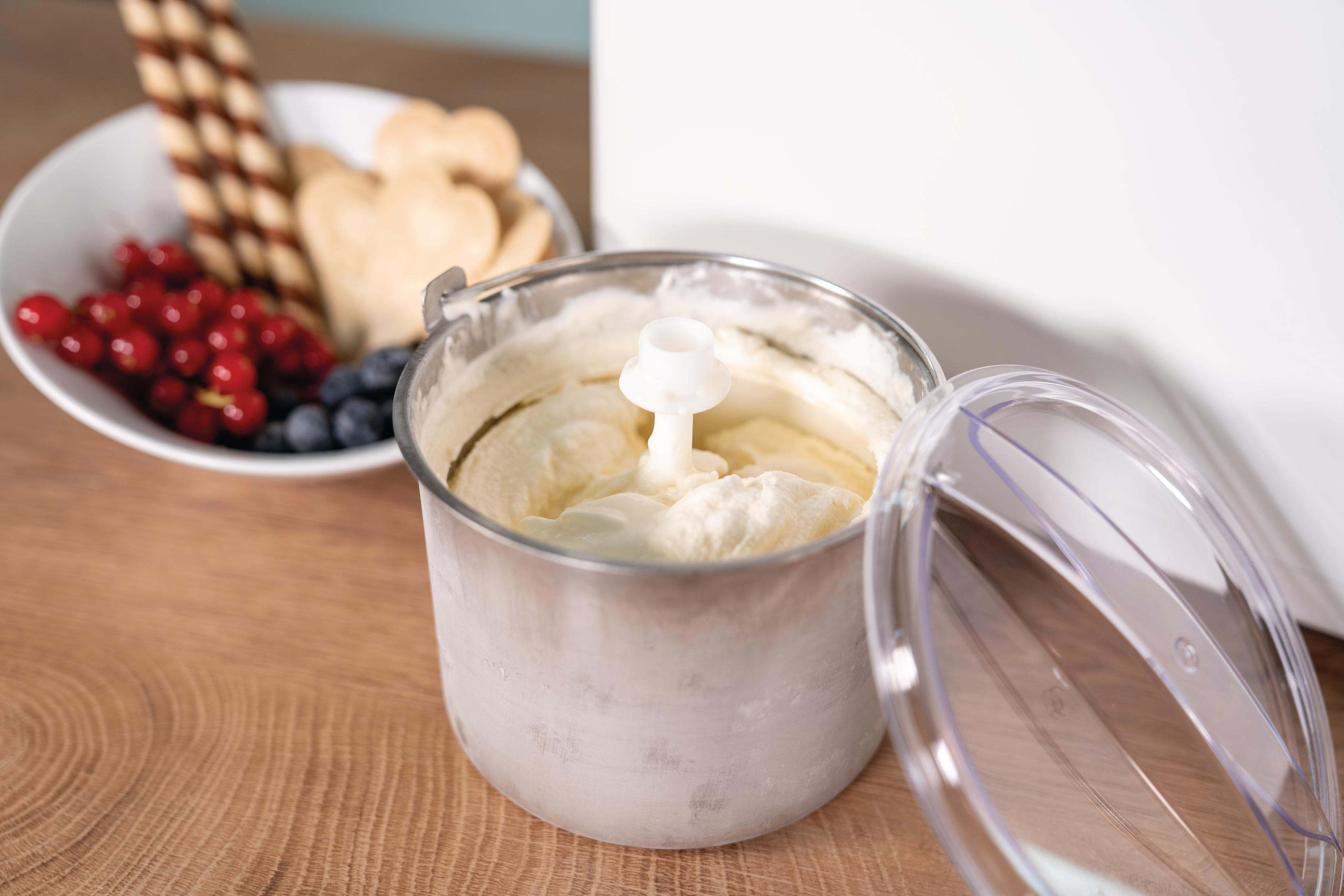 Maszyna do lodów z otwartym pojemnikiem, lodami w środku i składnikami na drewnianym stole.