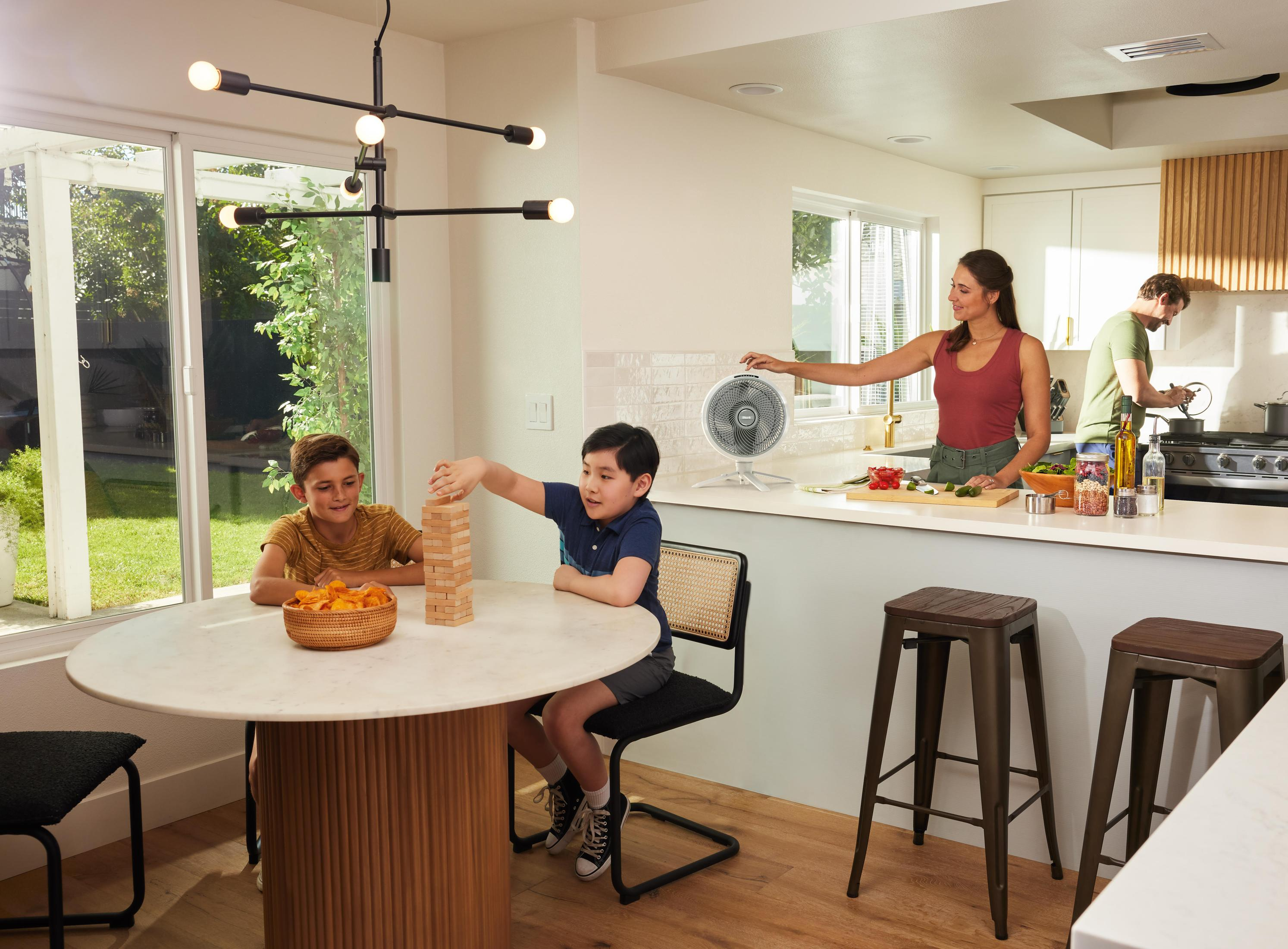 Rodzina gra w Jengę i gotuje w nowoczesnej kuchni. Dwóch chłopców gra w Jengę.