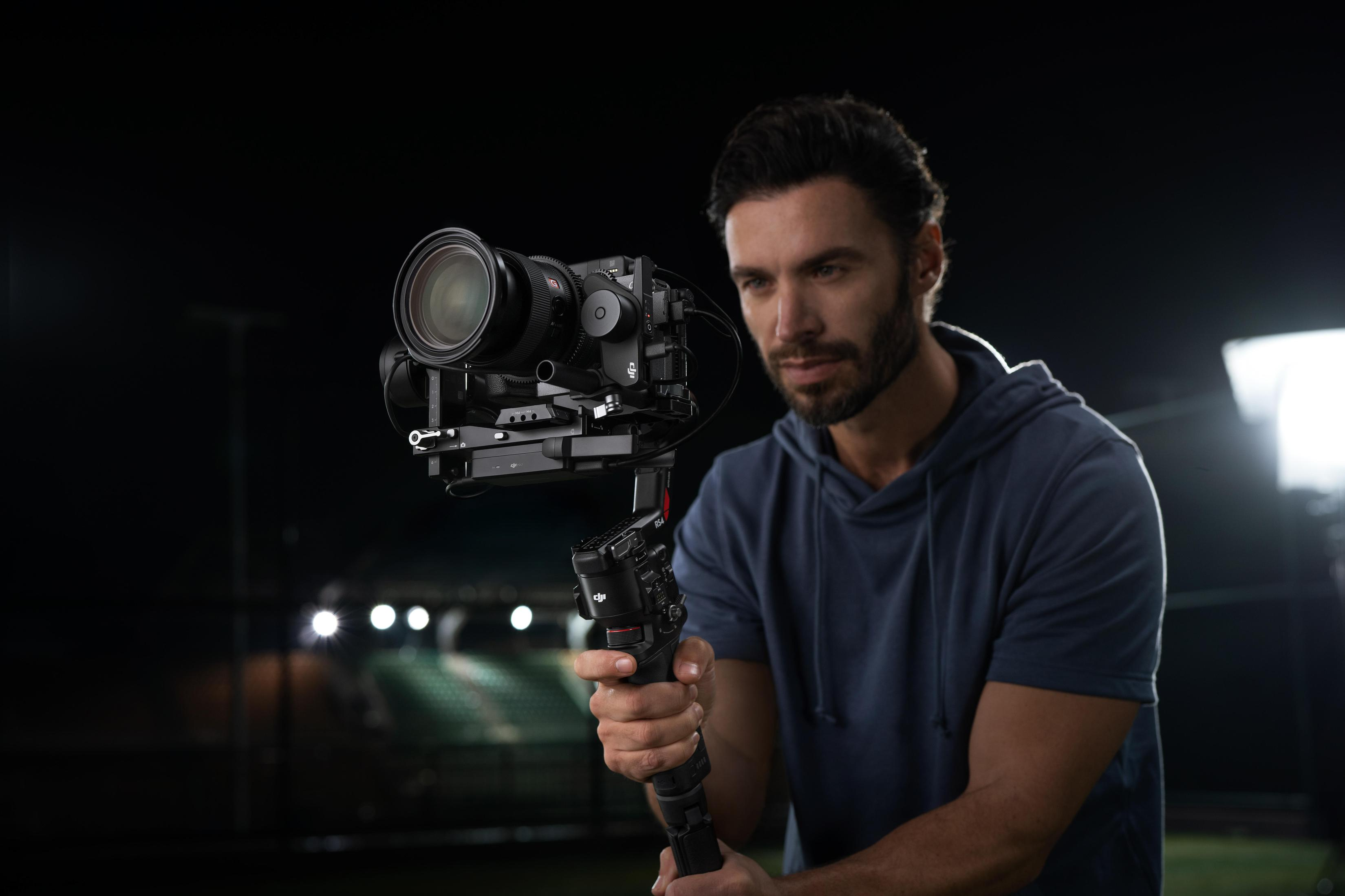 Mann filmt mit Kamera auf Gimbal, Nachtszene mit Lichtern.