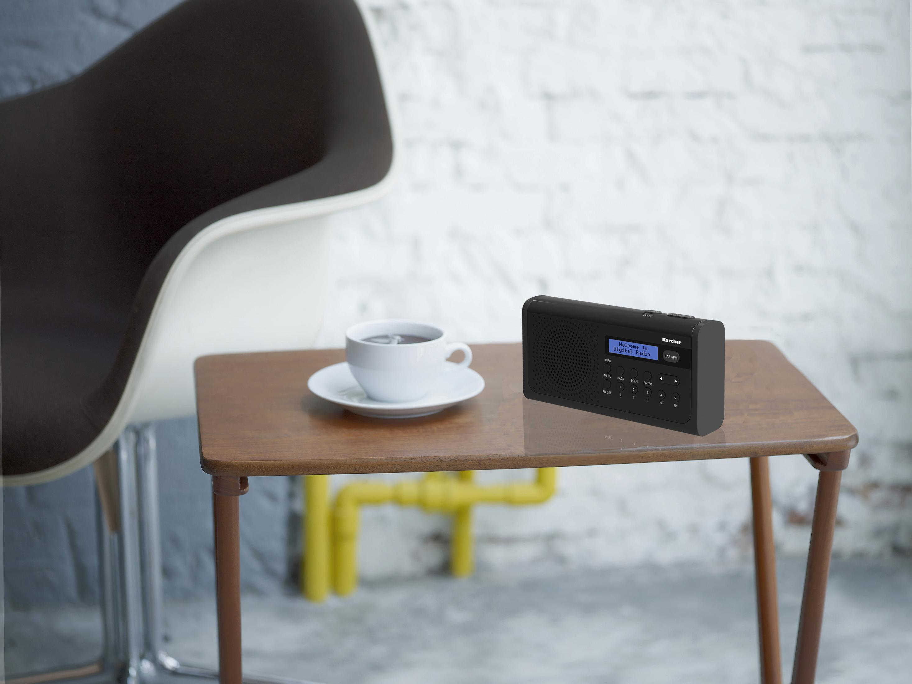Radio noire sur une table en bois, avec une tasse et une plante.