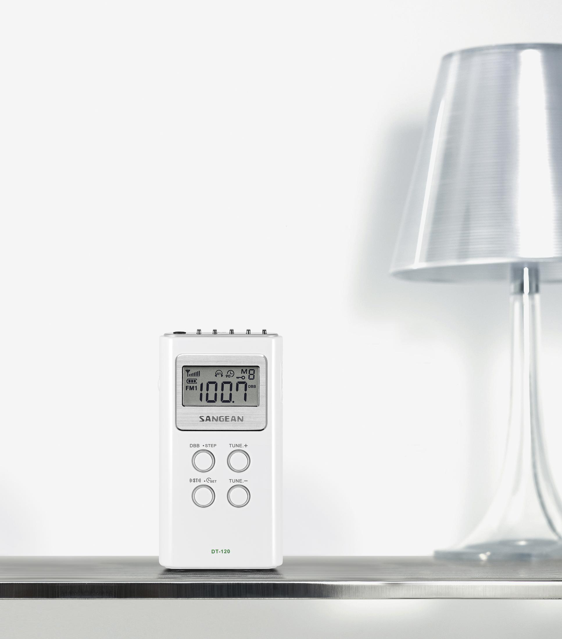 Ein weißes Sangean DT-120 Radio steht auf einem Regal neben einer Lampe.
