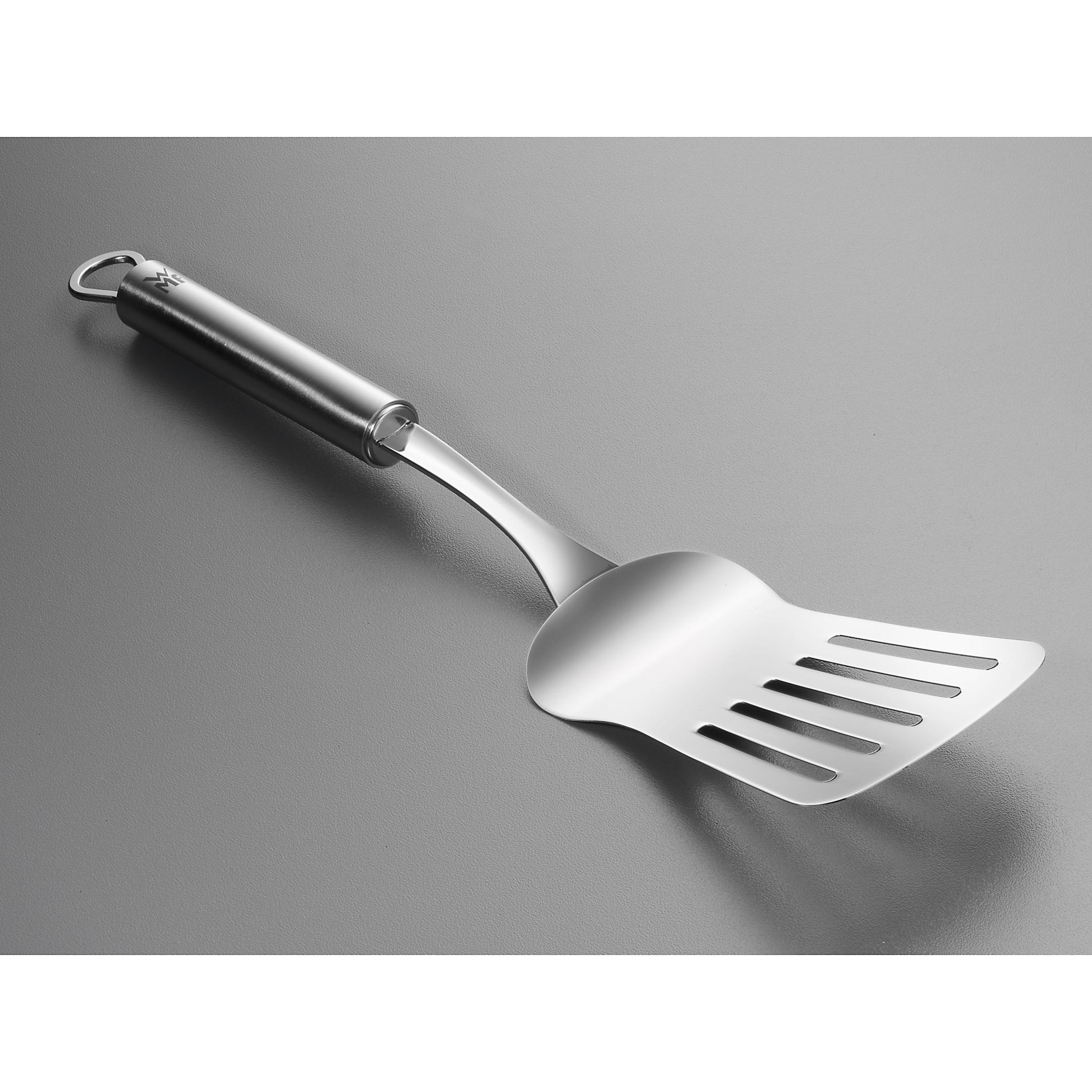Yuvalı gümüş metal spatula. Gri bir yüzey üzerinde duruyor.