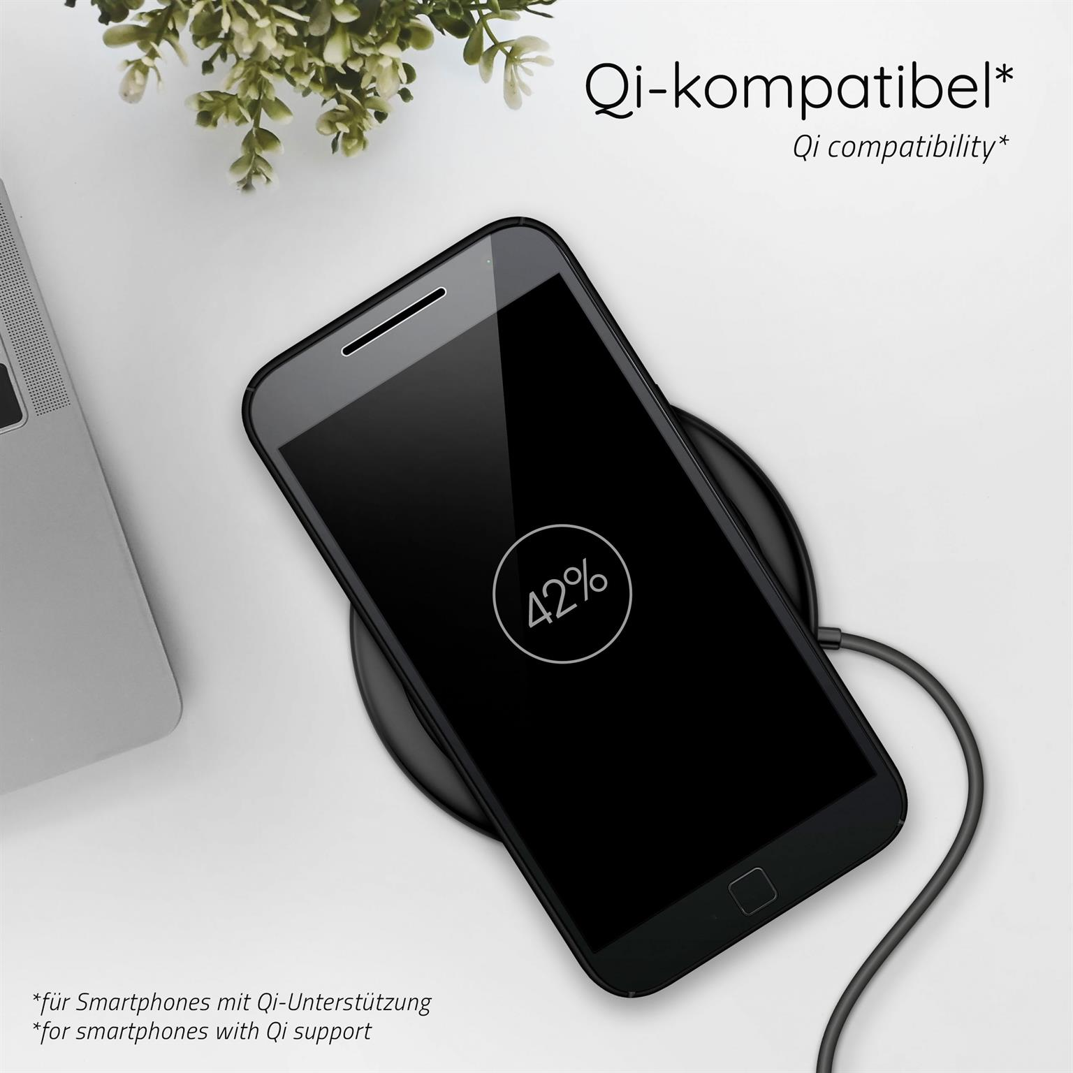Ein schwarzes Smartphone, das kabellos geladen wird und 42 % Akku anzeigt. Ein weißer Tisch und eine Pflanze sind im Bild.