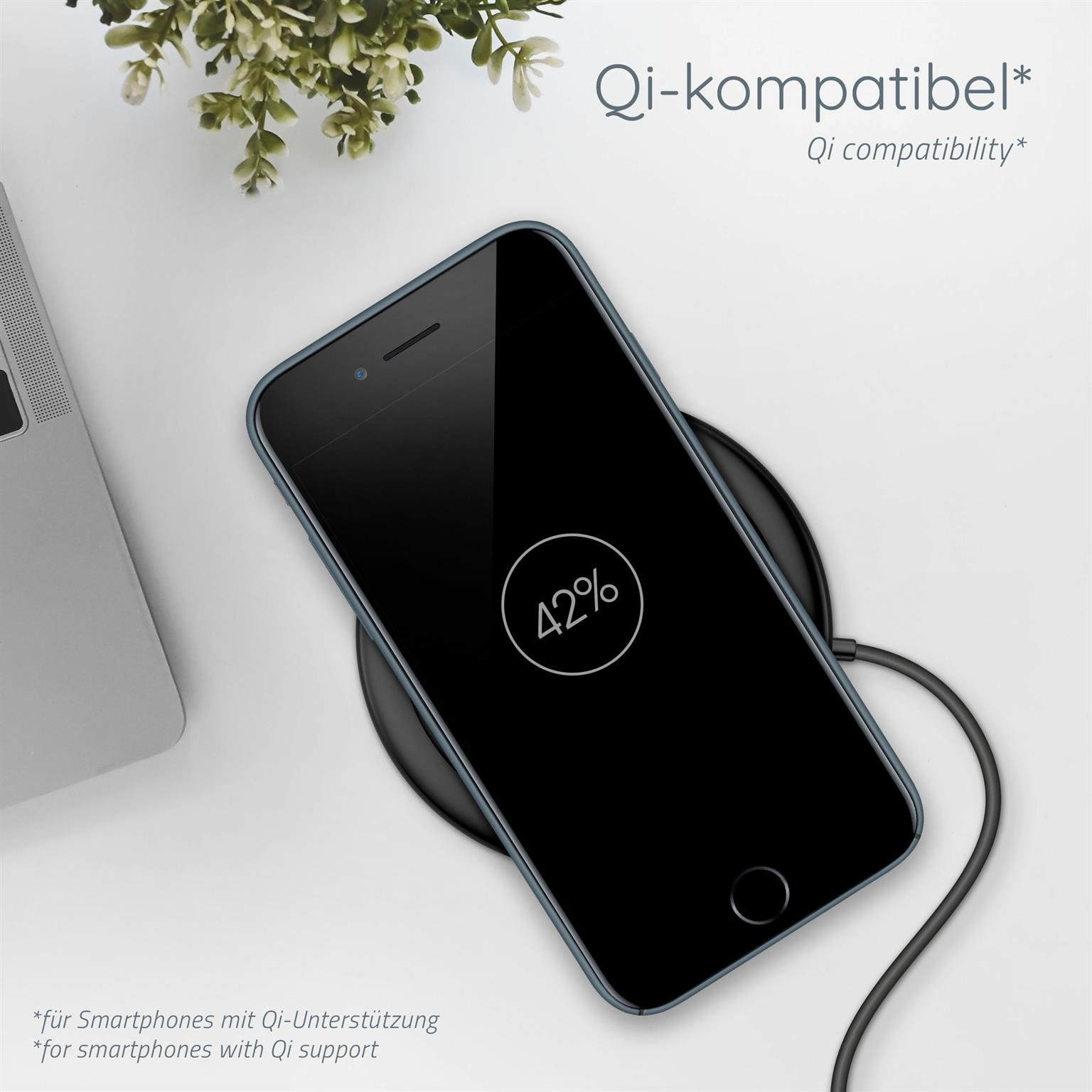 Ein schwarzes Smartphone auf einem kabellosen Ladegerät zeigt 42% Ladung, mit einer Pflanze im Hintergrund.