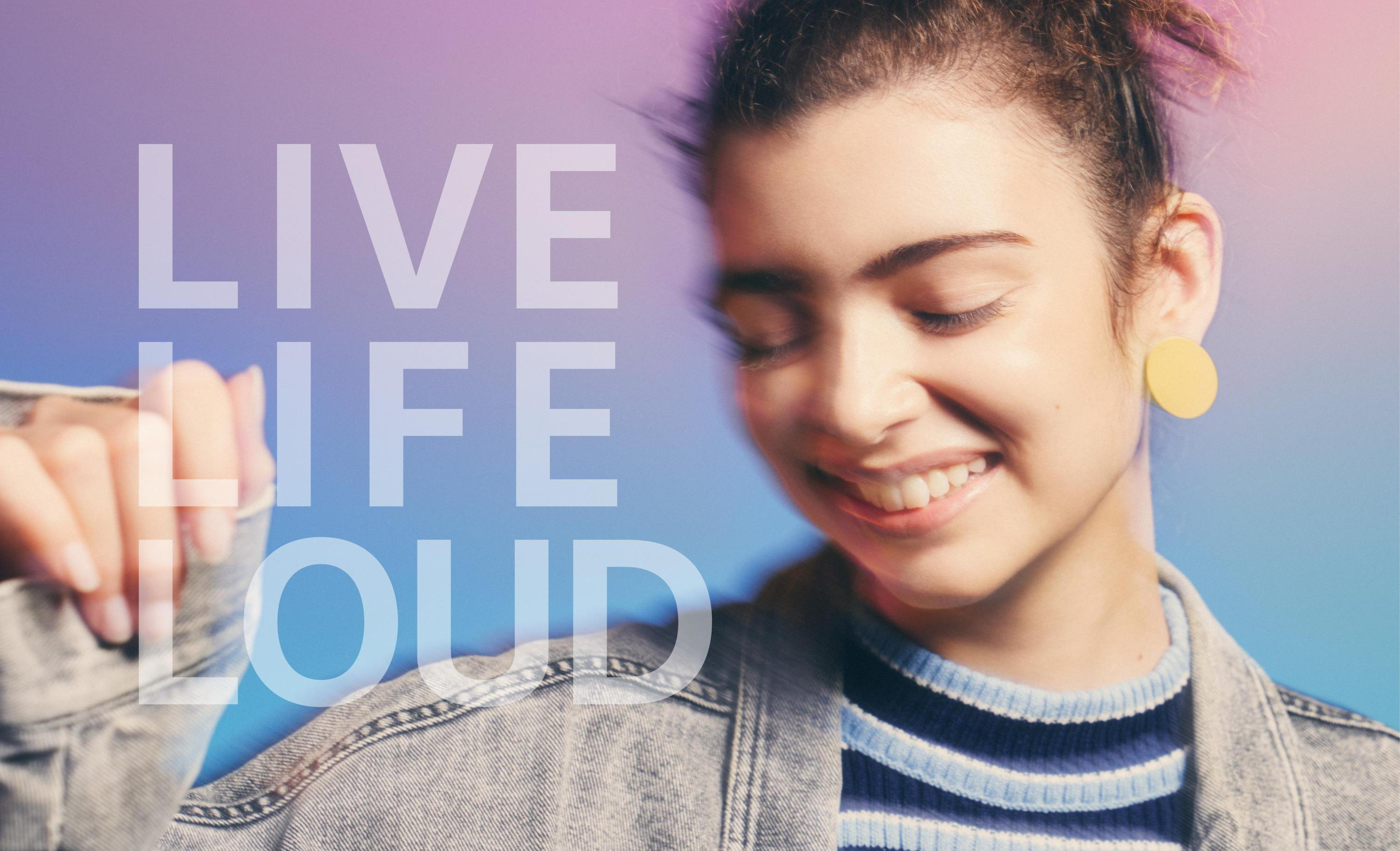 Una giovane donna sorridente, con il testo 'LIVE LIFE LOUD' in alto e uno sfondo sfumato blu-viola.