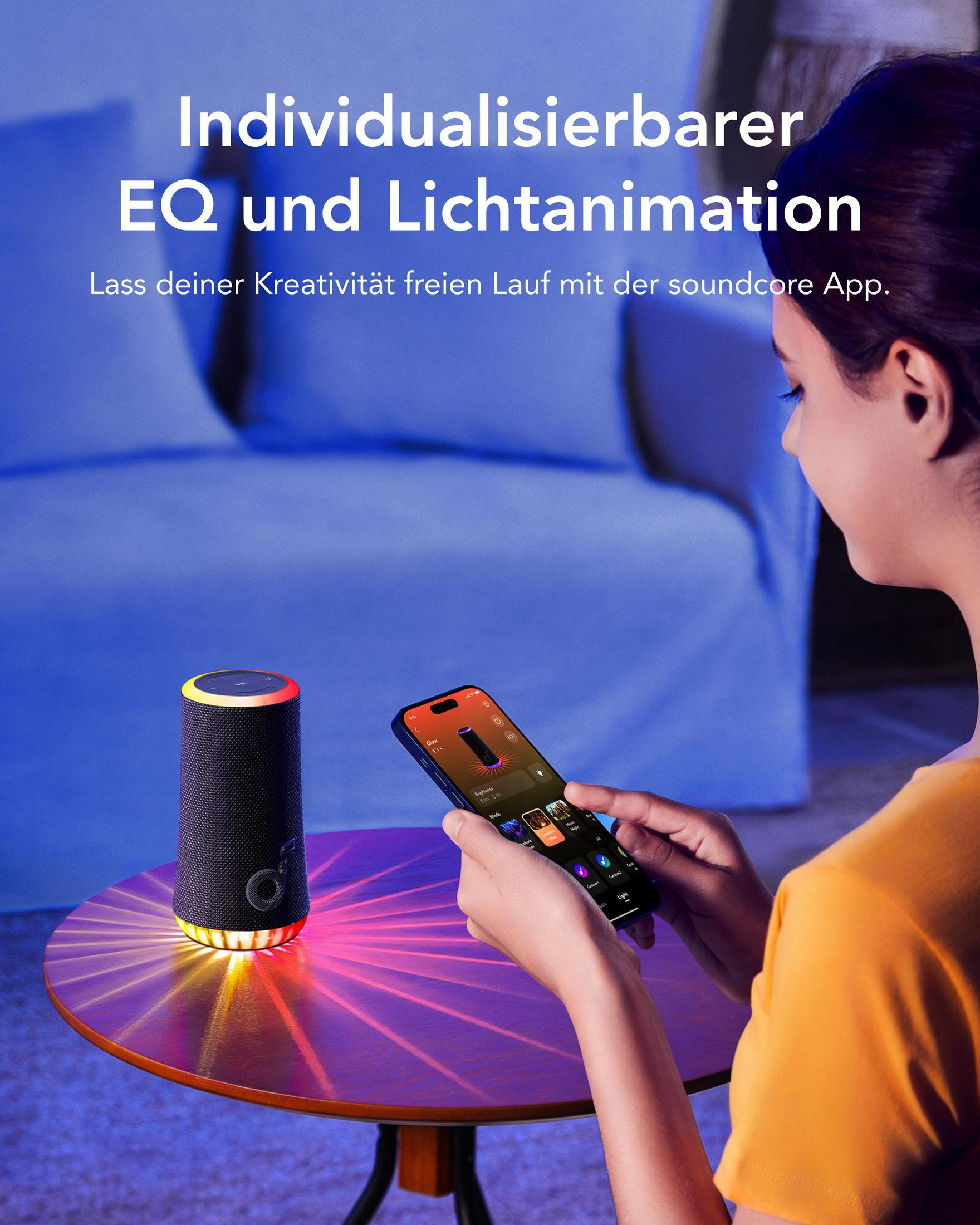 Kobieta używa telefonu do sterowania głośnikiem z kolorowymi światłami na stole.
