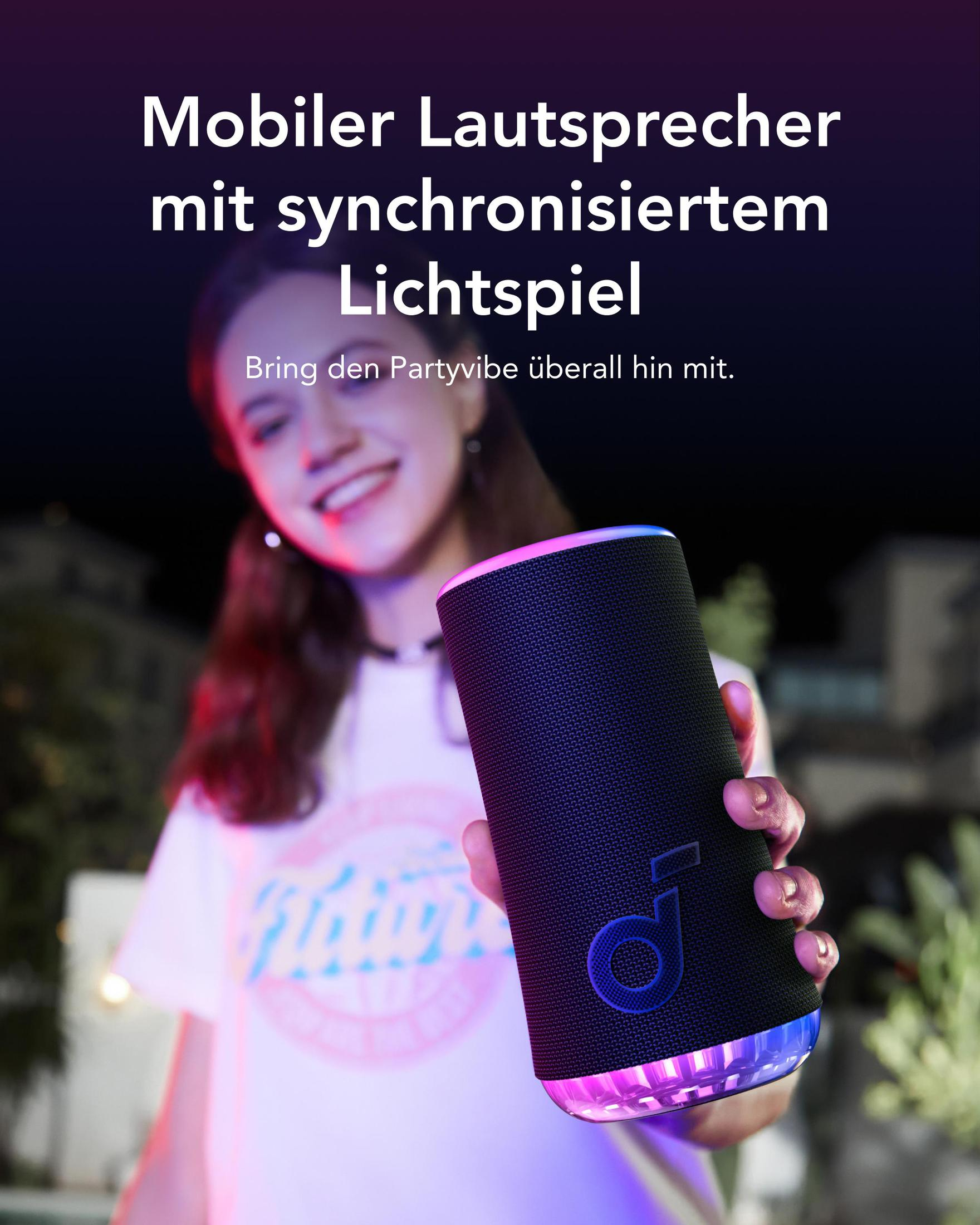 Kobieta trzymająca czarny głośnik z różowym i niebieskim światłem. Rozmyte tło.