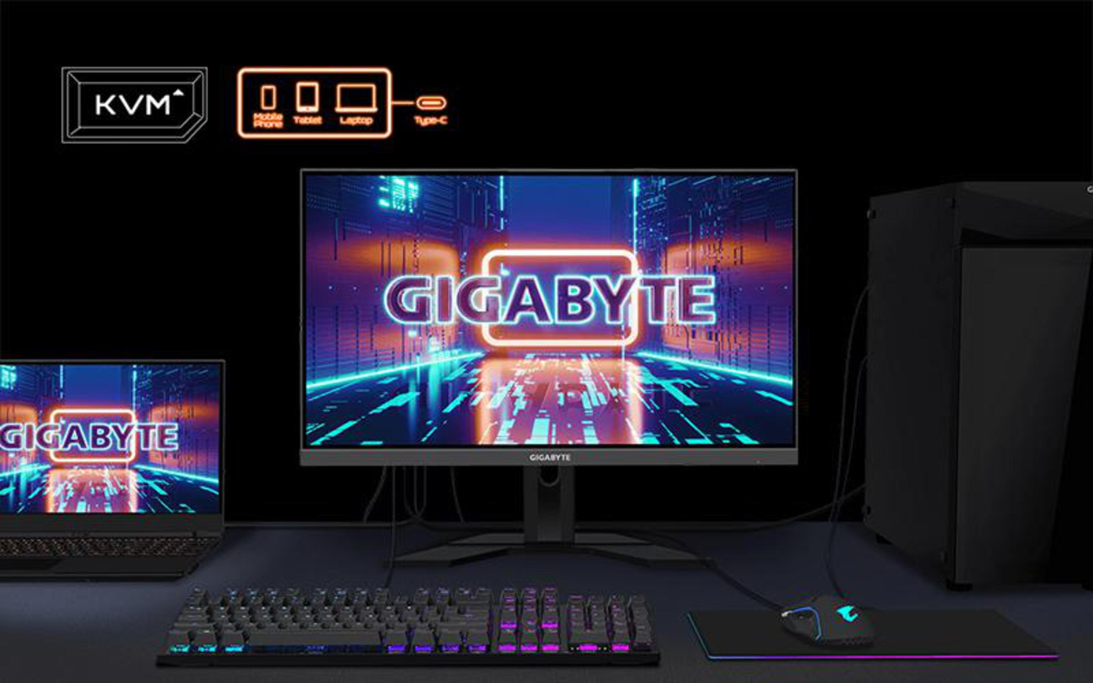 Un monitor visualizza il logo GIGABYTE, collegato a un laptop, tastiera e PC.