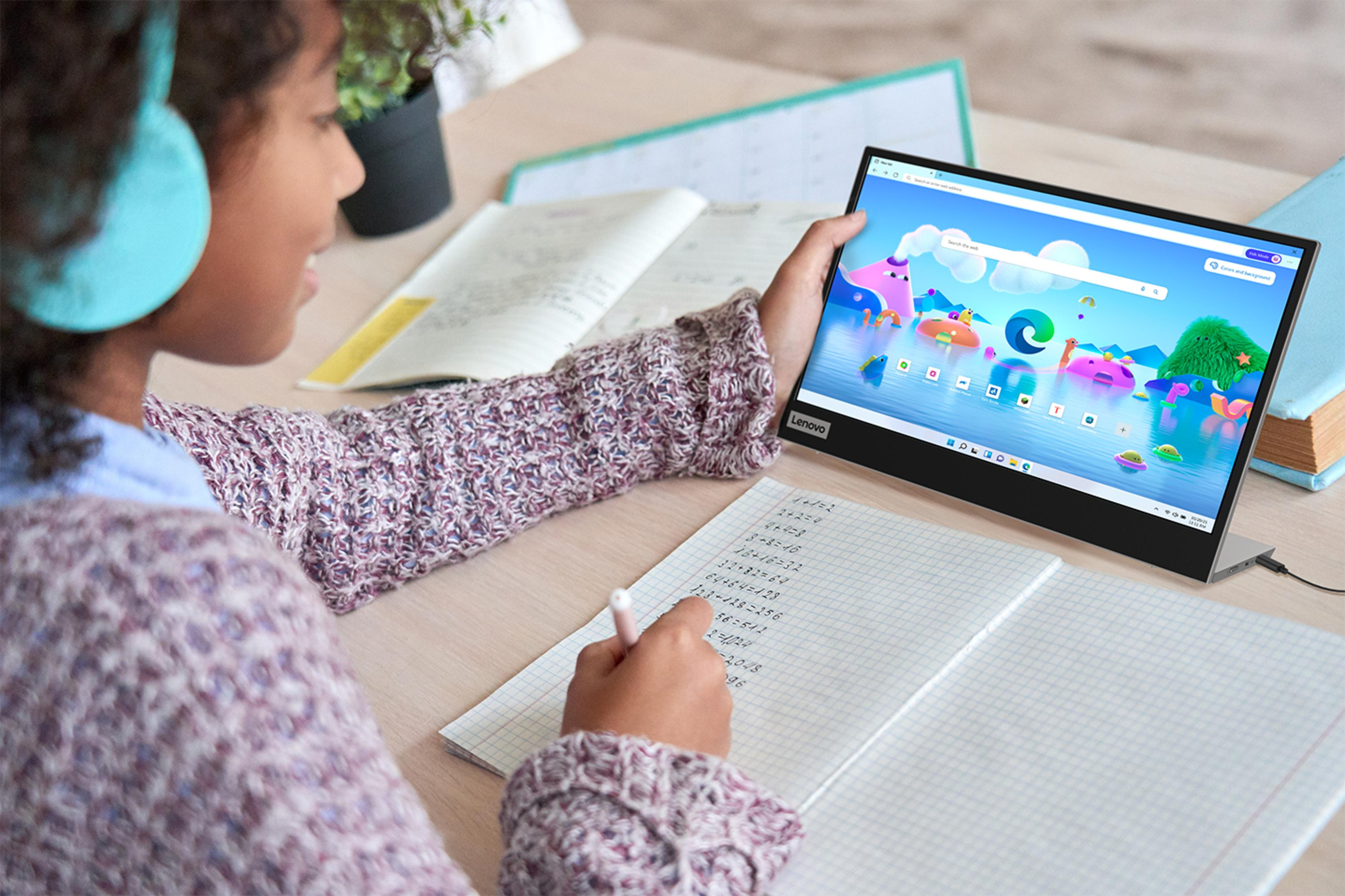 Dziewczyna pracuje na laptopie przy biurku z książkami. Zeszyt ma zadania matematyczne.