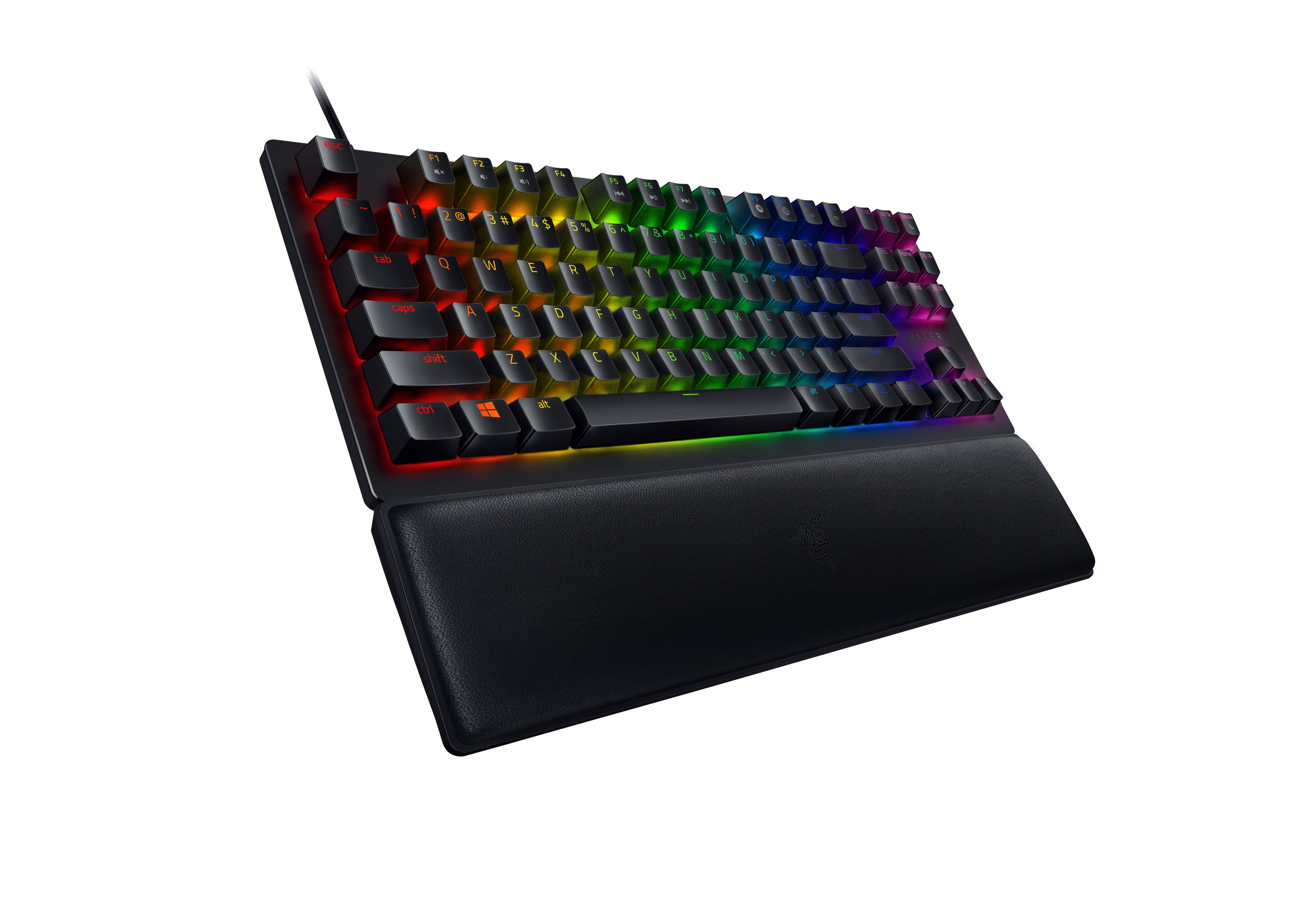 Schwarze Tastatur mit bunten beleuchteten Tasten und Handgelenkauflage auf weißer Oberfläche.