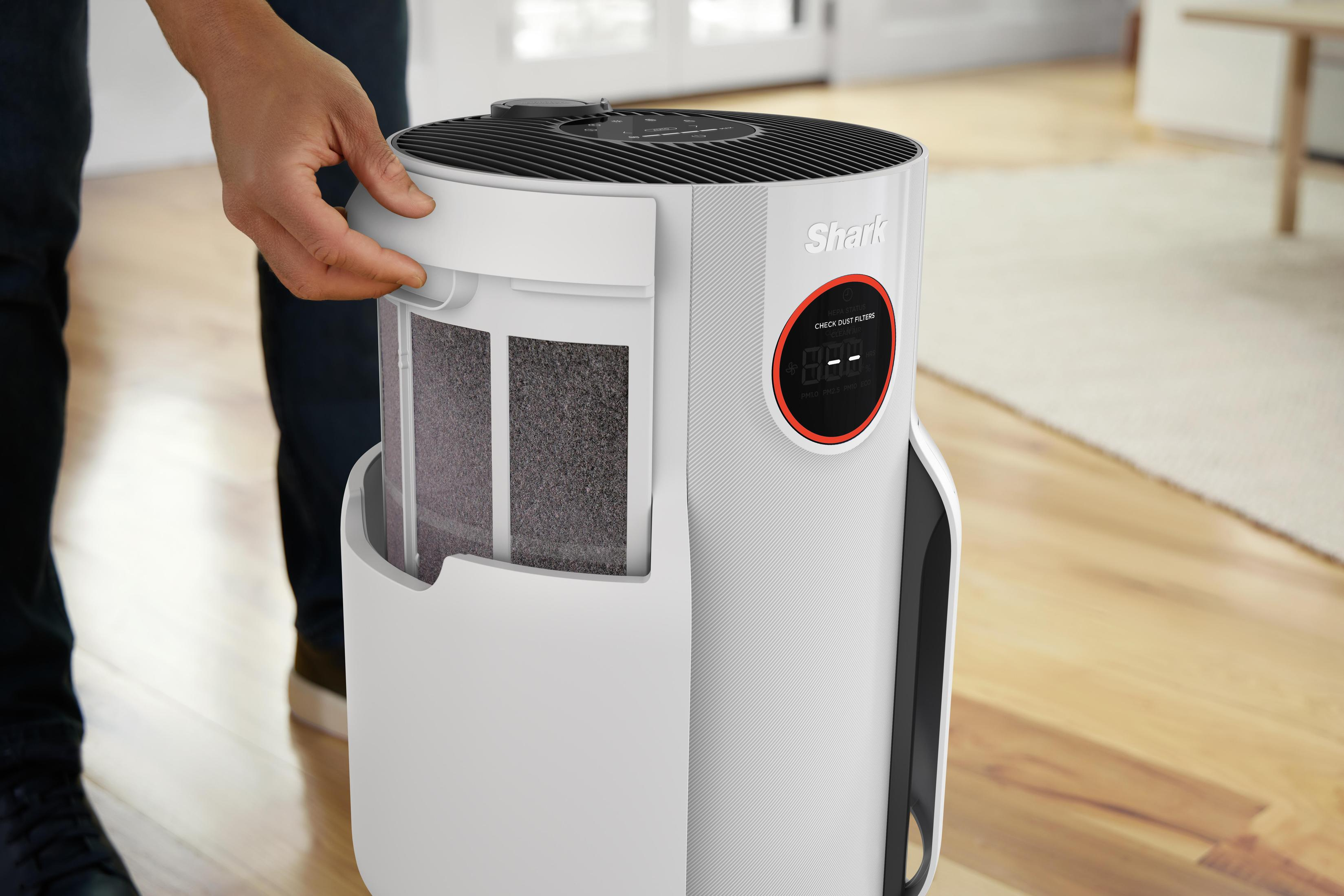 Person öffnet Luftreiniger. Der Filter ist sichtbar. Der Reiniger ist weiß und schwarz.