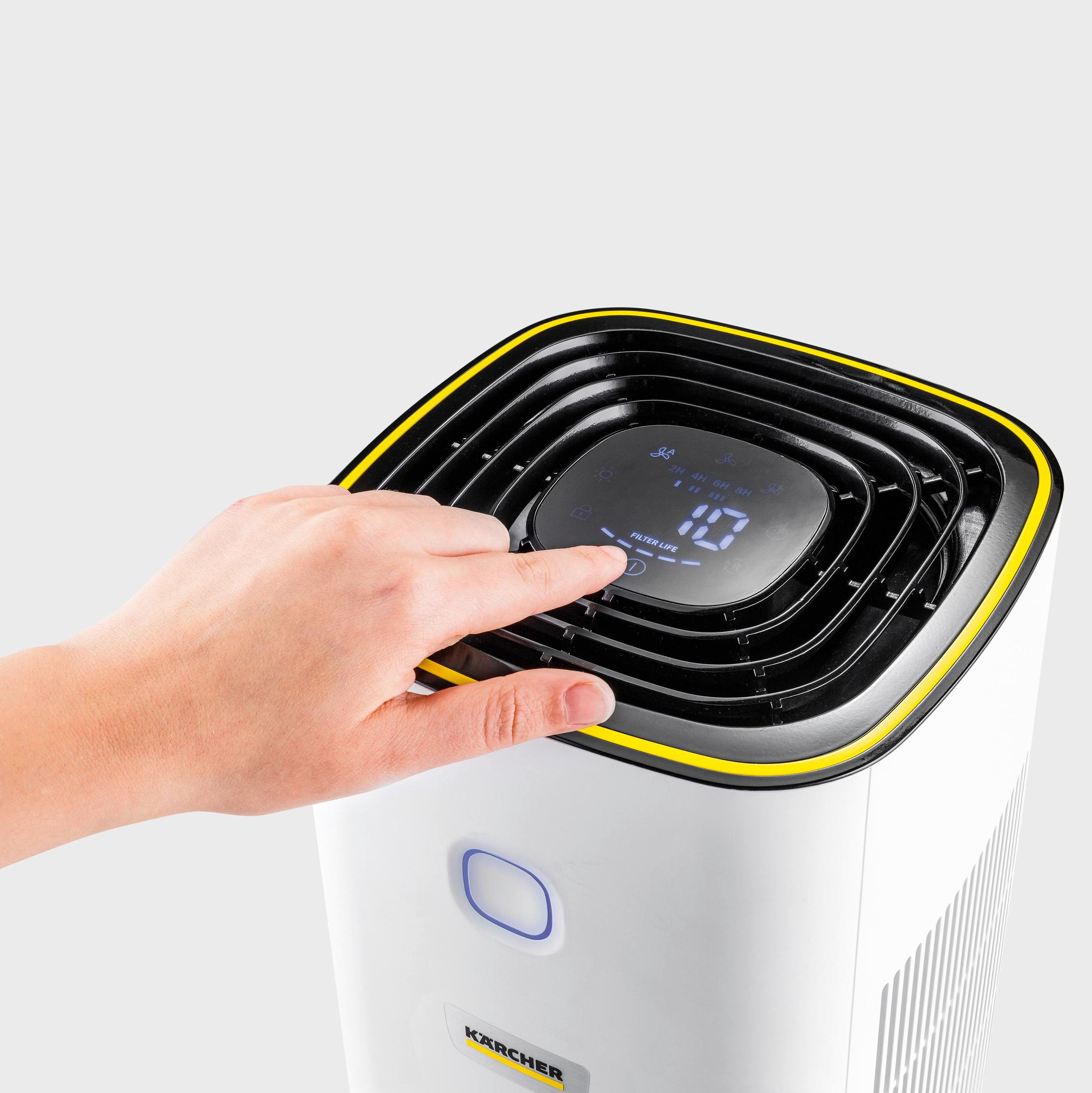 Eine Hand drückt die Ein-/Aus-Taste eines weißen und schwarzen Luftreinigers mit Digitalanzeige.