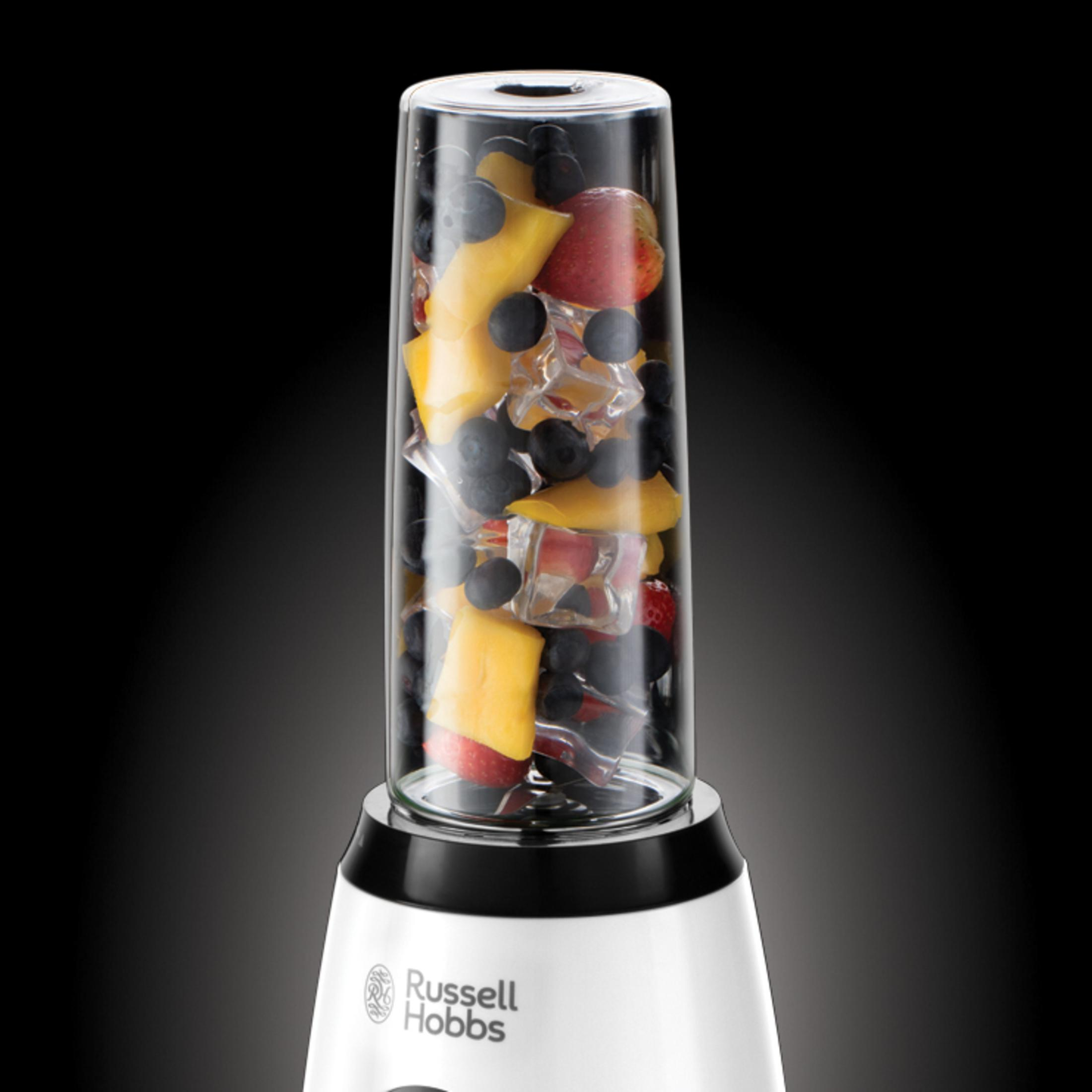 İçinde meyve ve buz olan blender. Blender beyaz bir tabana ve cam bir kaba sahip.