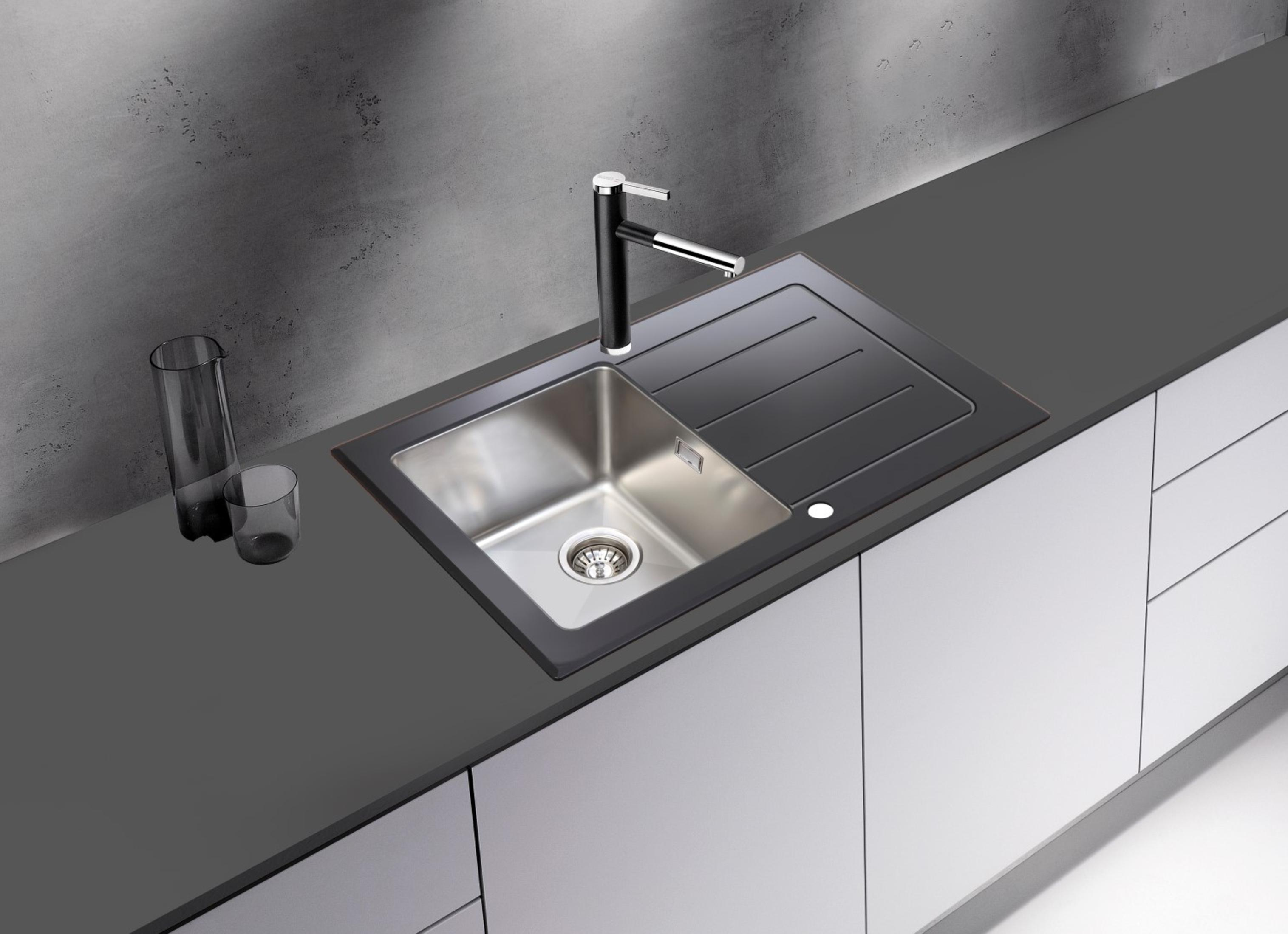 Edelstahlspüle in einer dunkelgrauen Arbeitsplatte mit schwarzem Wasserhahn. Weiße Schränke unten.