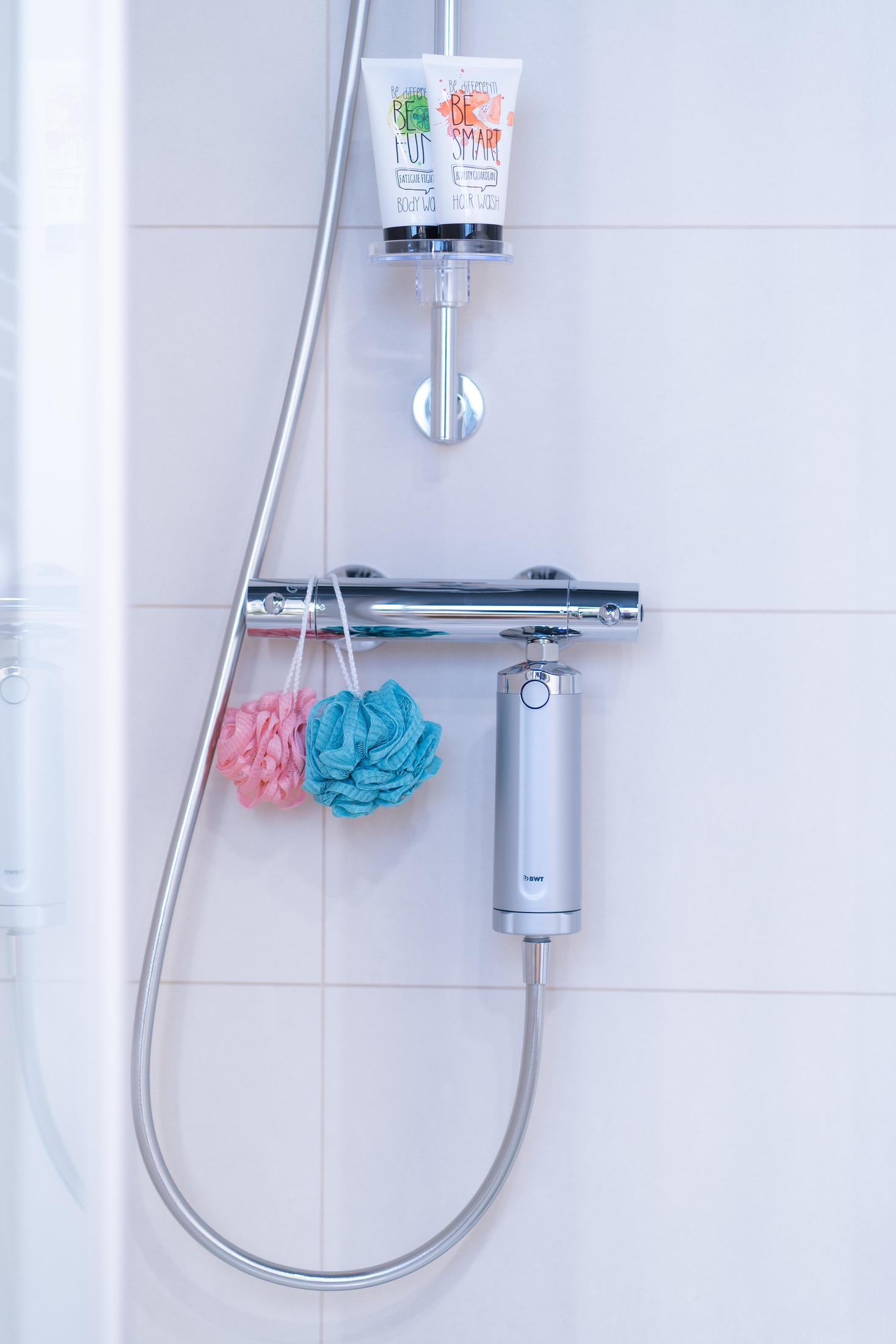 Prysznic ze srebrną głowicą, dwiema myjkami i dwiema tubkami żelu pod prysznic.
