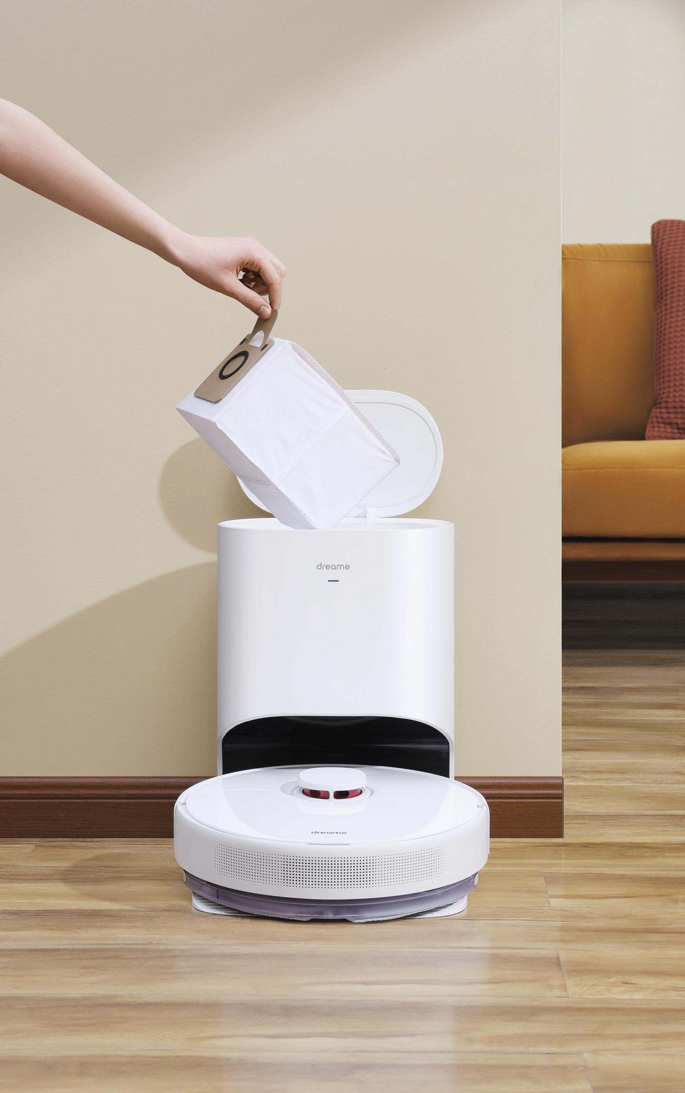 Una persona está poniendo una bolsa en una aspiradora robot blanca.