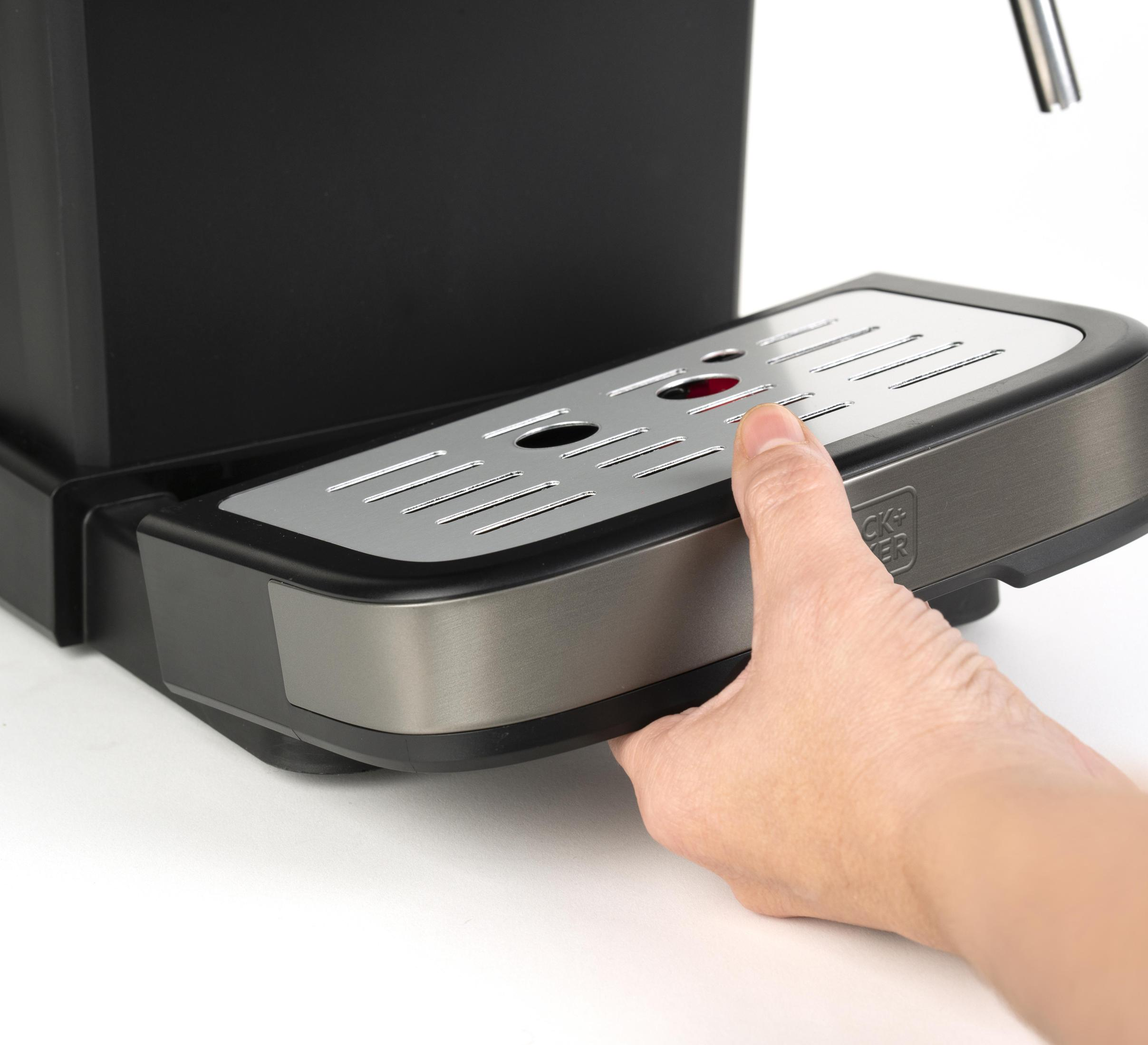 Ręka wyciąga tackę ociekową z czarnego ekspresu do kawy.