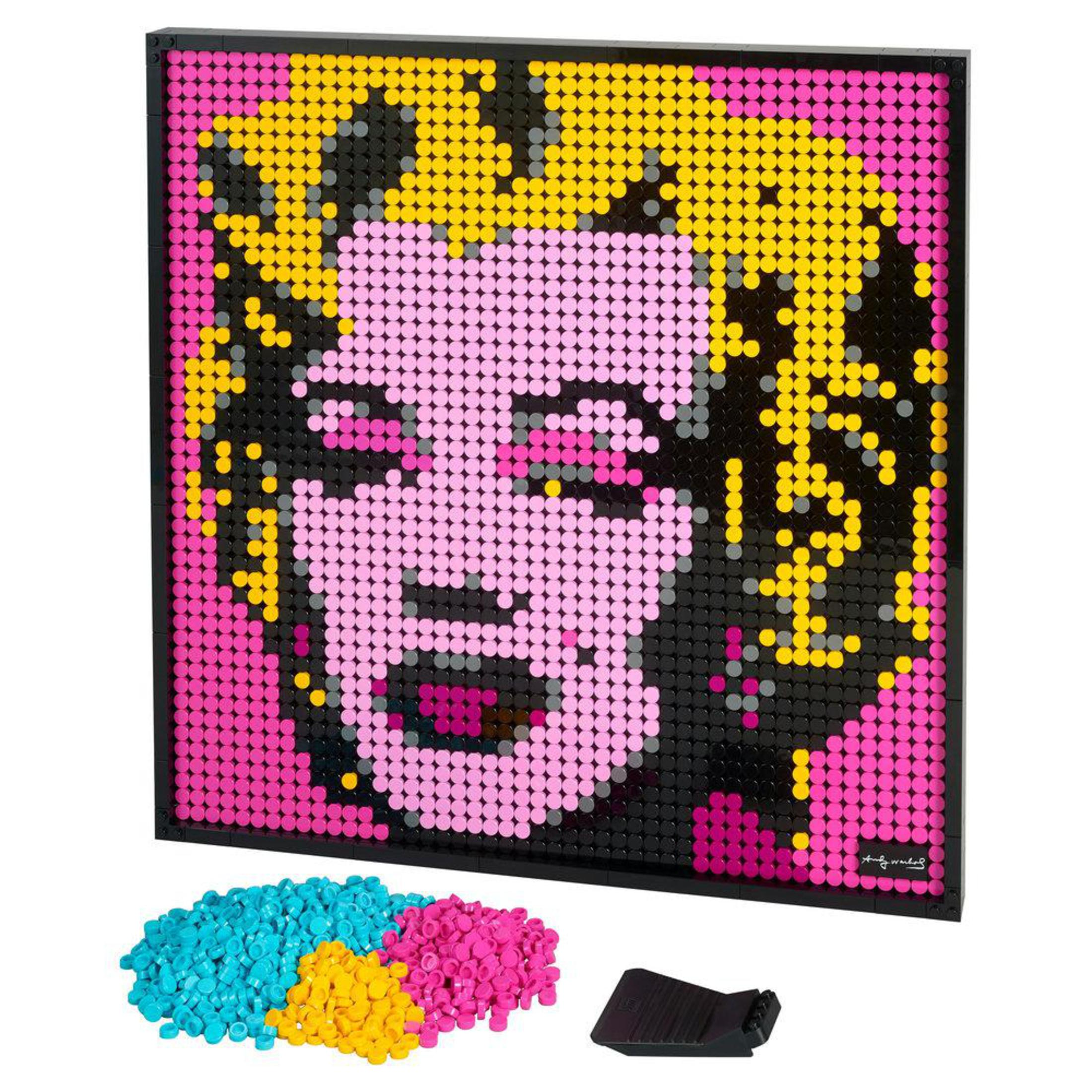 Dzieło sztuki Lego z twarzą Marilyn Monroe, z rozrzuconymi kolorowymi klockami.