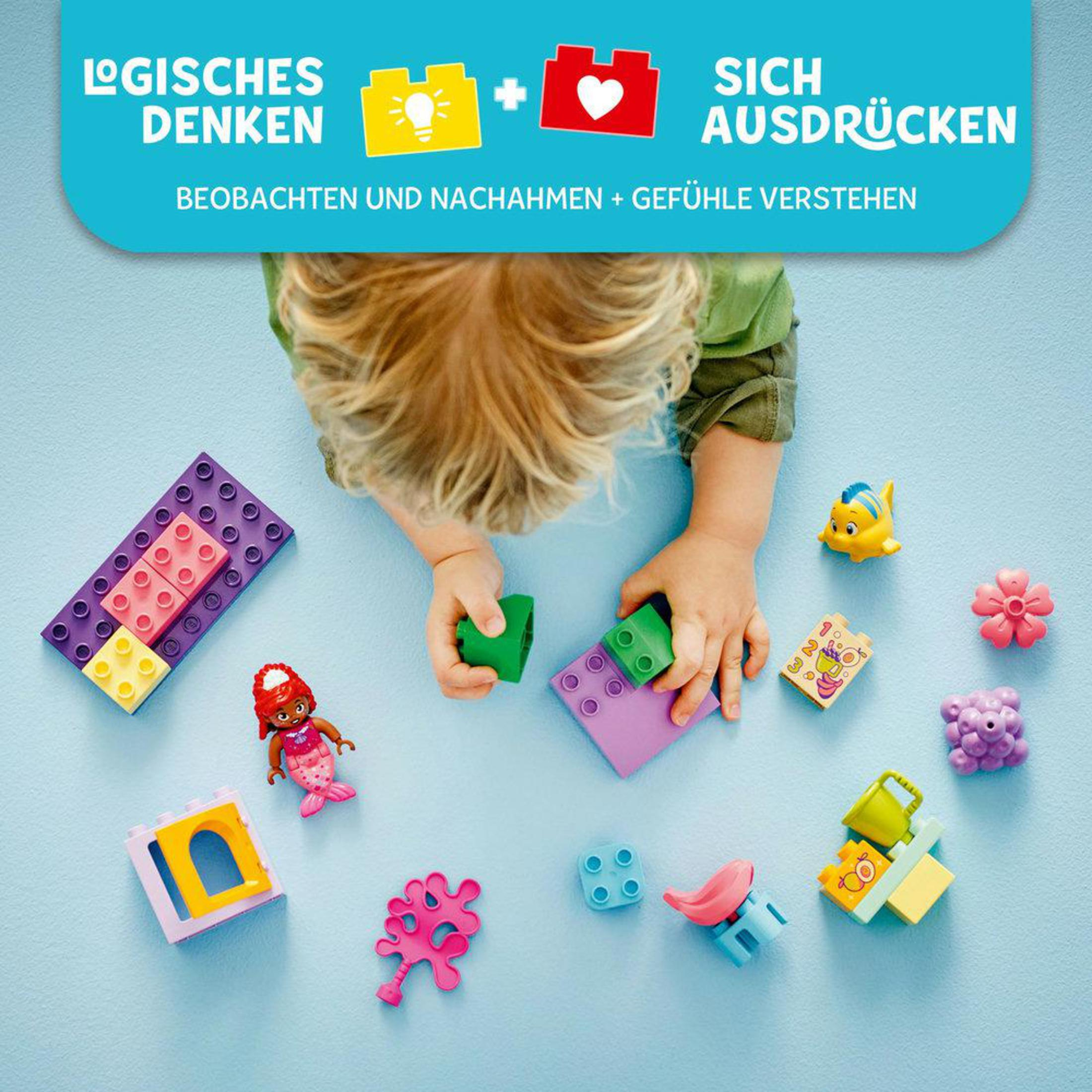 Kolorowe klocki Lego z rękami dziecka sięgającymi po nie, na niebieskiej powierzchni.